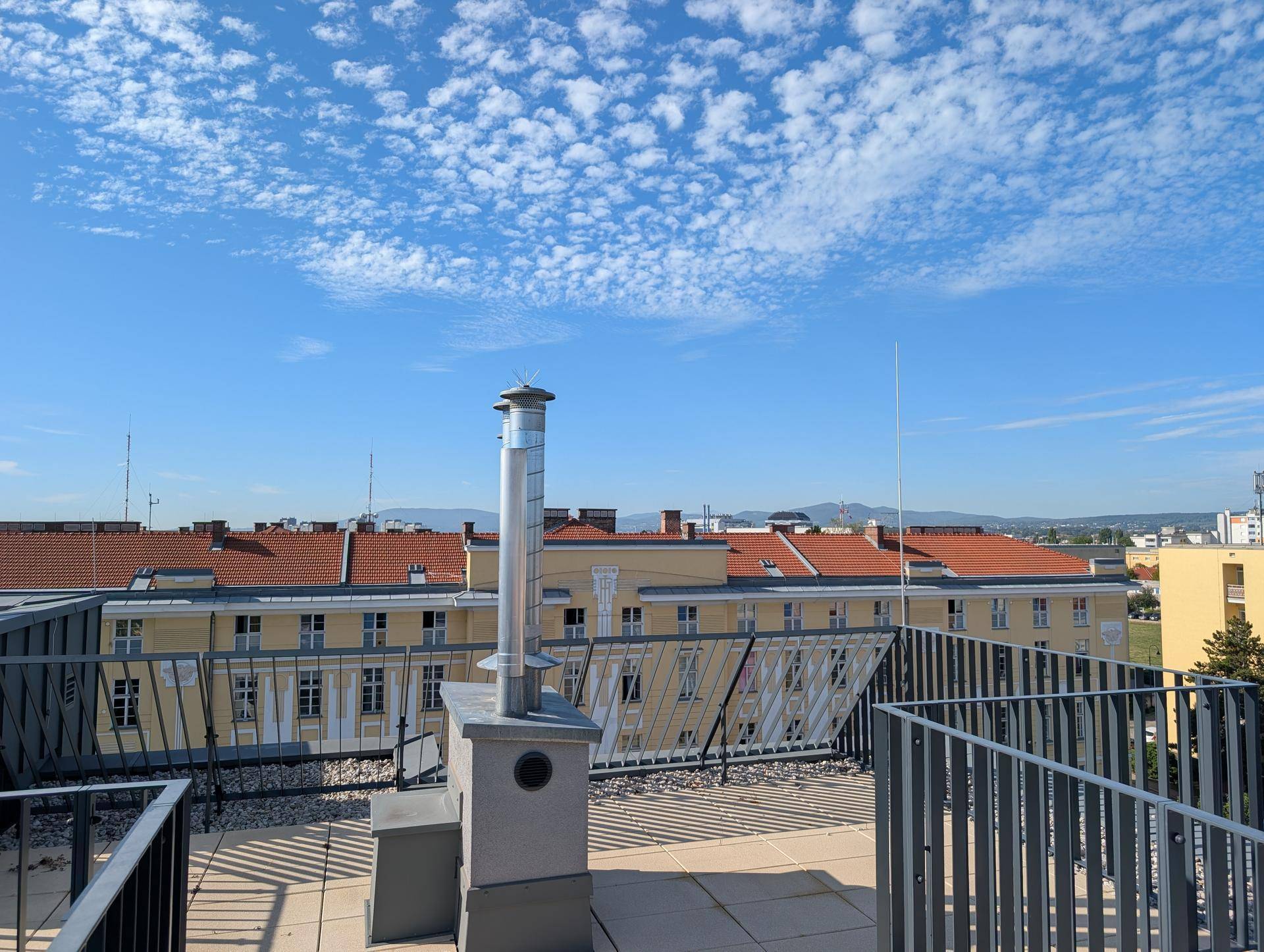 Dachterrasse mit moderner Architektur und weitem Blick über die Stadt an einem sonnigen Tag.