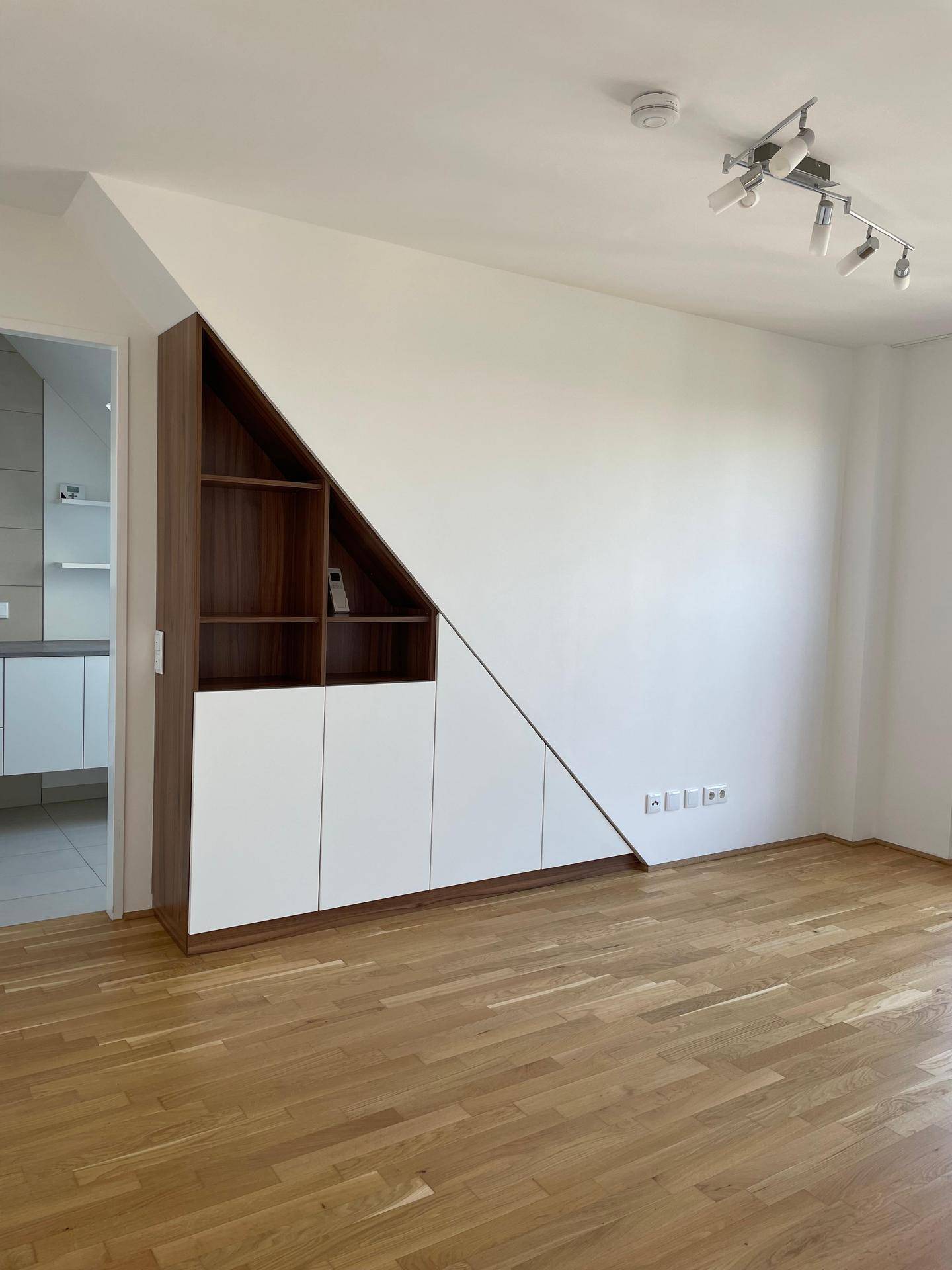 Geräumiger Raum mit Holzboden und clever integrierten Einbauschränken unter der Dachschräge.