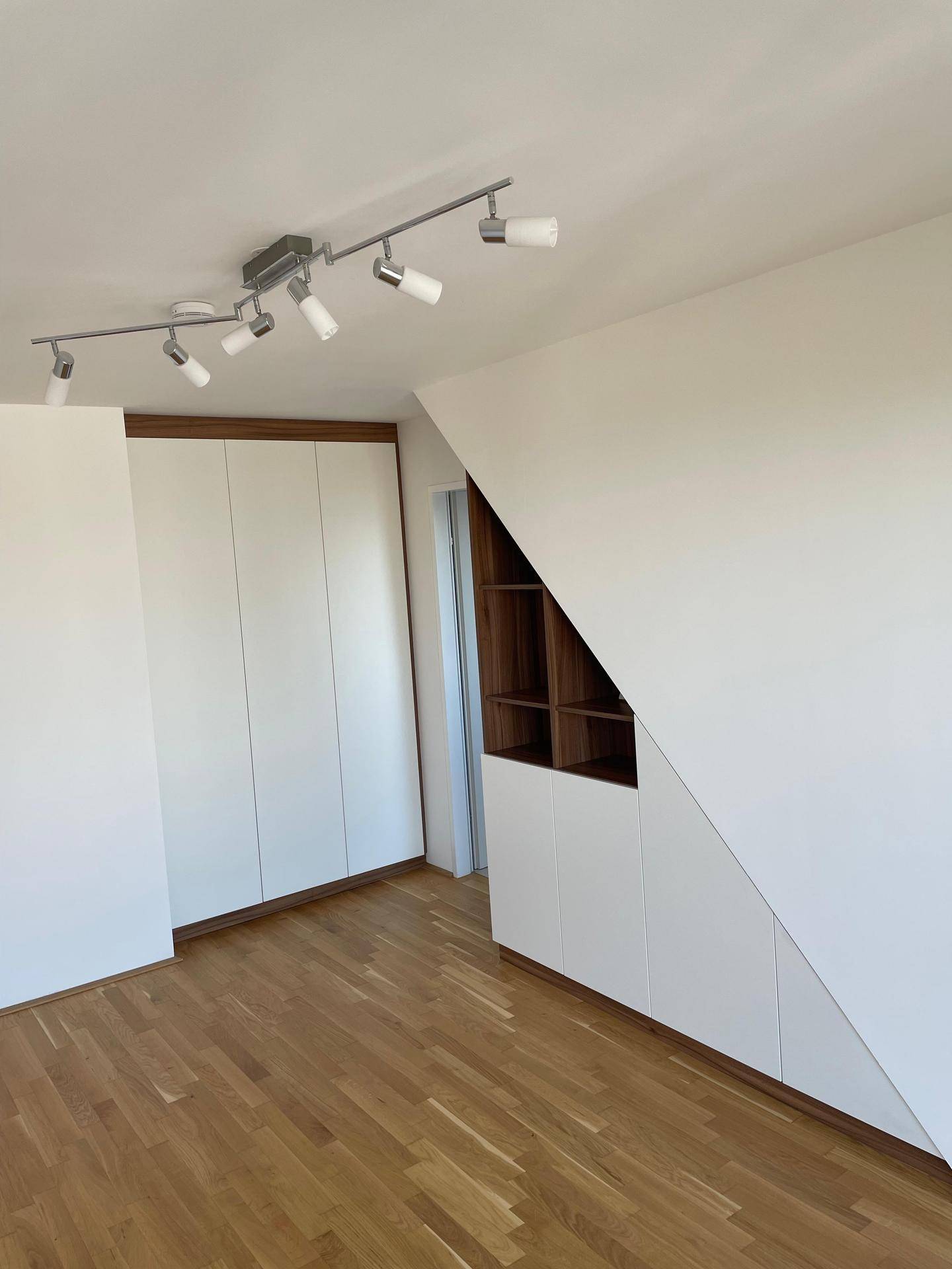 Helles Schlafzimmer mit großem Einbauschrank und maßgefertigtem Stauraum unter der Dachschräge.