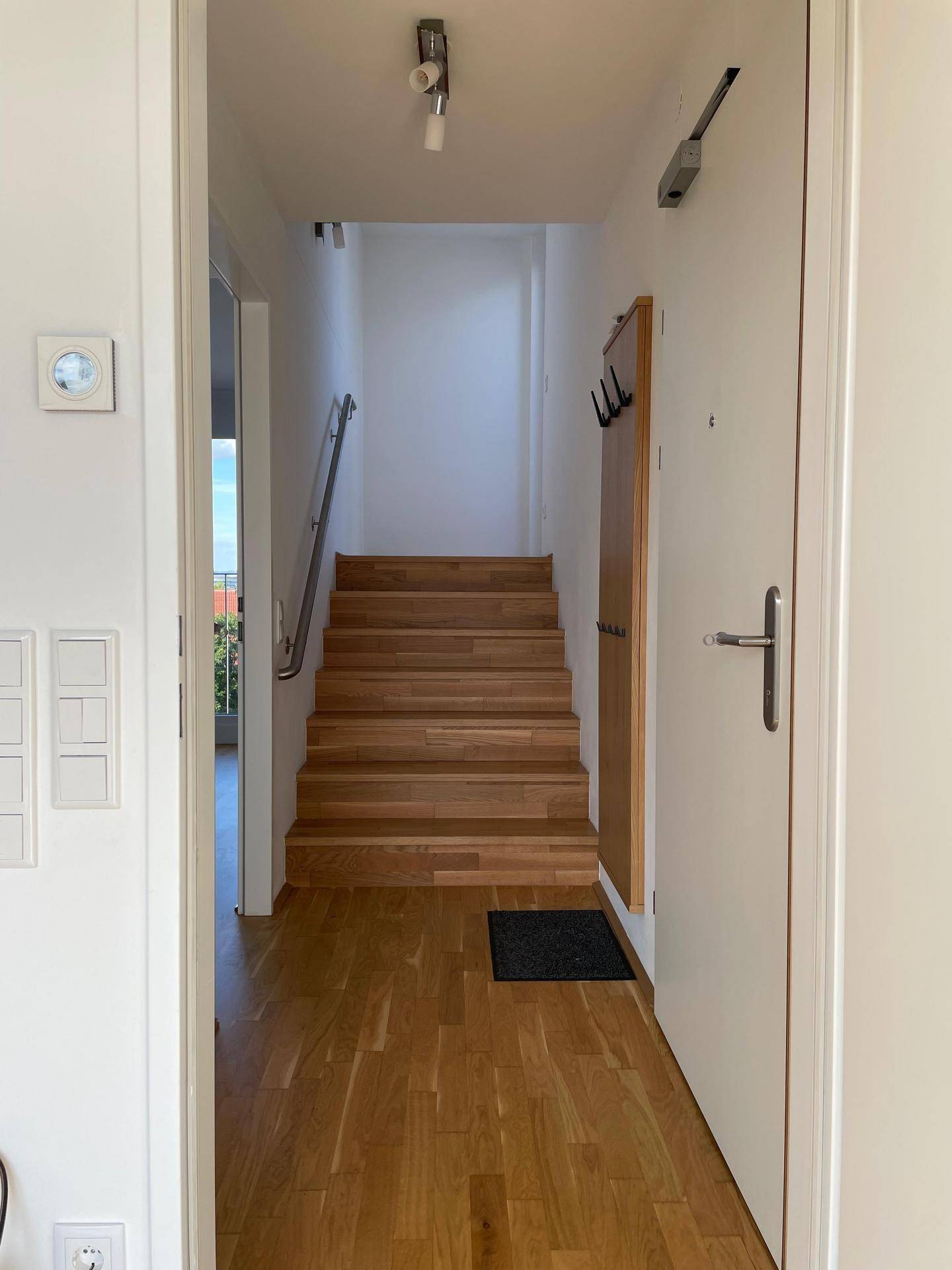 Heller Flur mit Holztreppe und Parkettboden, der in die obere Etage des Hauses führt.