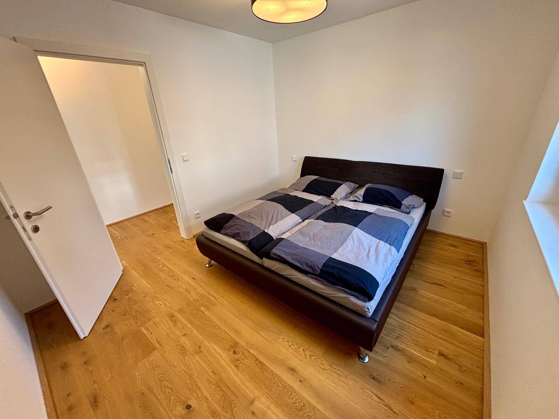 Helles Schlafzimmer mit Holzboden und Doppelbett, bereit zur Einrichtung.