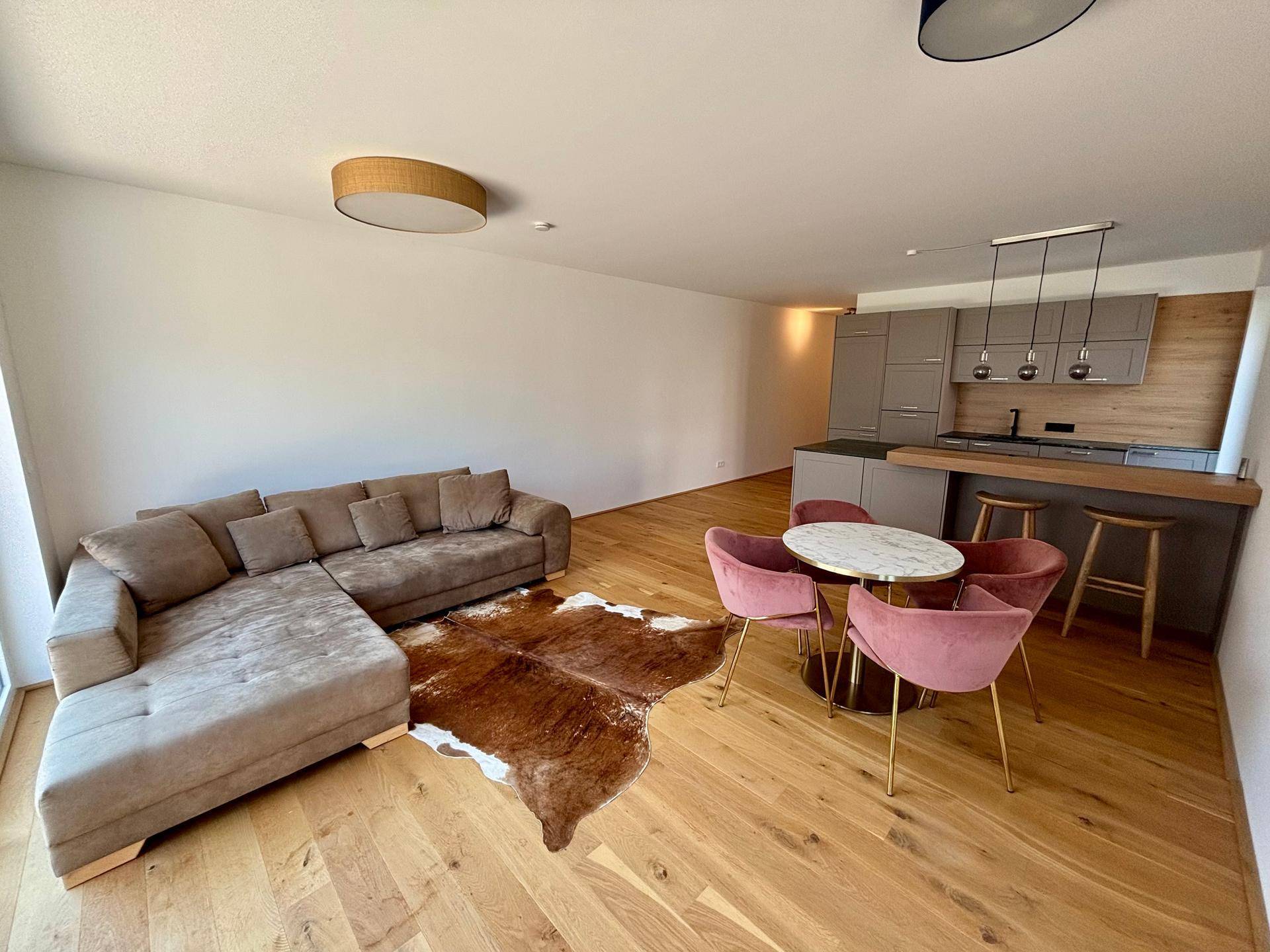 Gemütlicher Wohnbereich mit Ecksofa, Esstisch und offener Küche im Hintergrund.