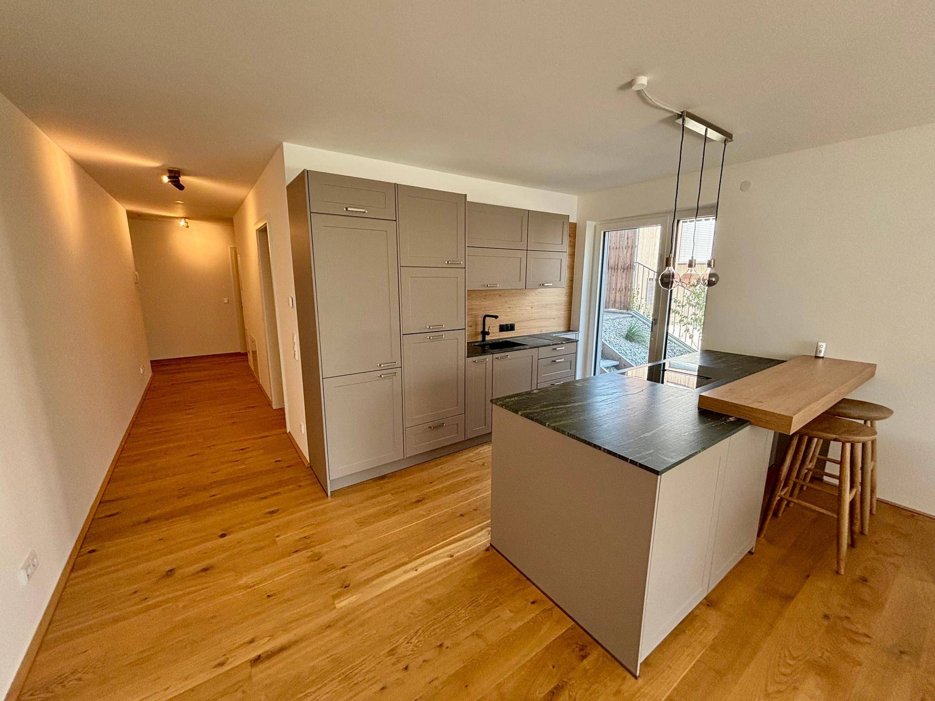 Moderne Einbauküche mit Kücheninsel, Holzboden und Blick in den Flur.