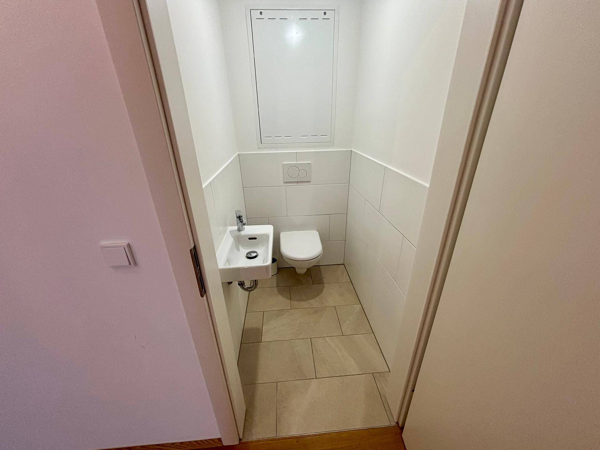 Kleines Gäste-WC mit wandhängendem WC und Handwaschbecken.