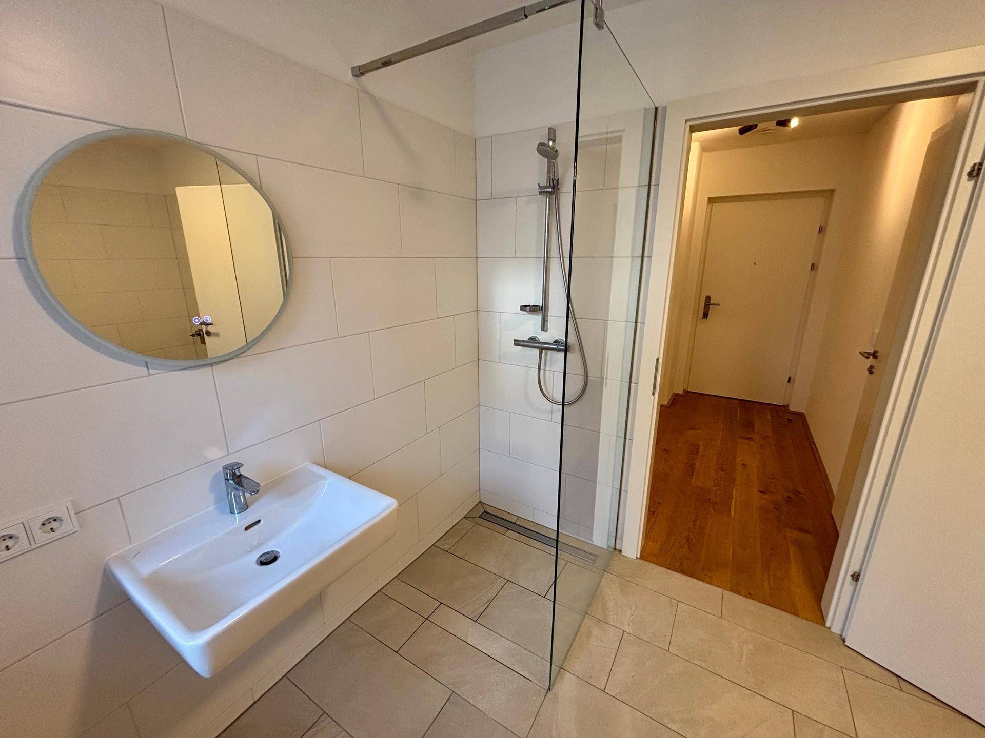 Modernes Badezimmer mit begehbarer Dusche, Einzelwaschbecken und weißen Fliesen.
