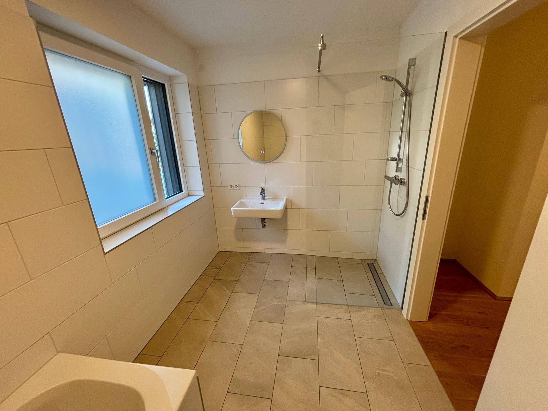 Geräumiges Badezimmer mit Fenster, begehbarer Dusche und Badewanne.