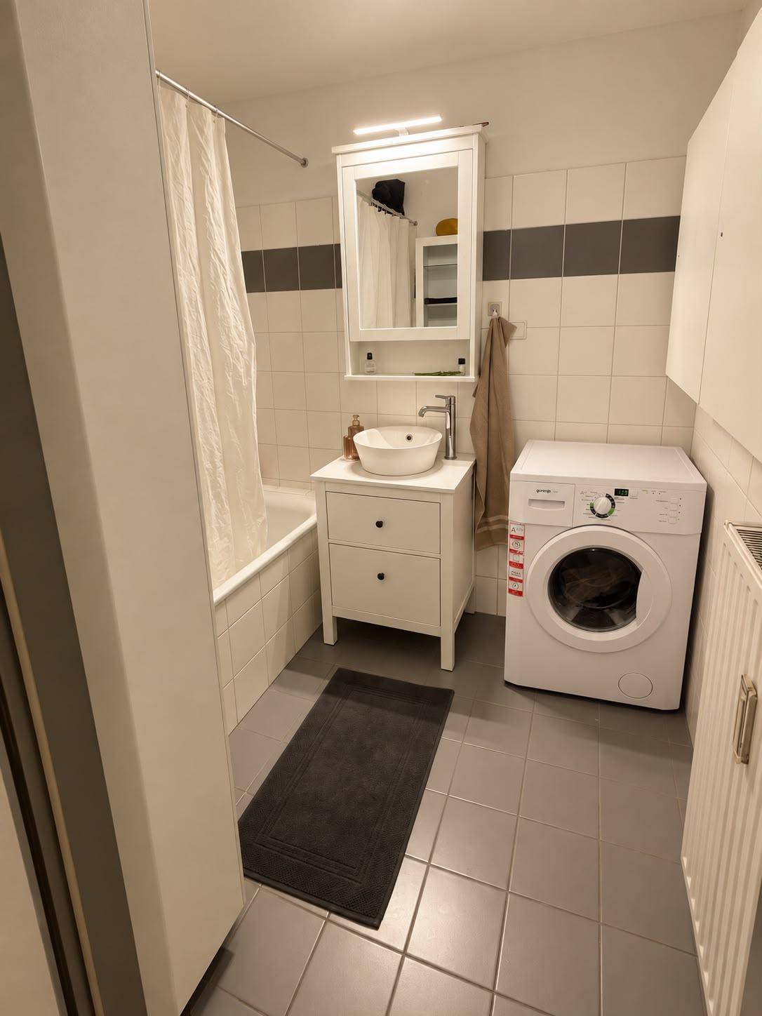 Funktionales Badezimmer mit Badewanne, Waschbecken und Waschmaschine.