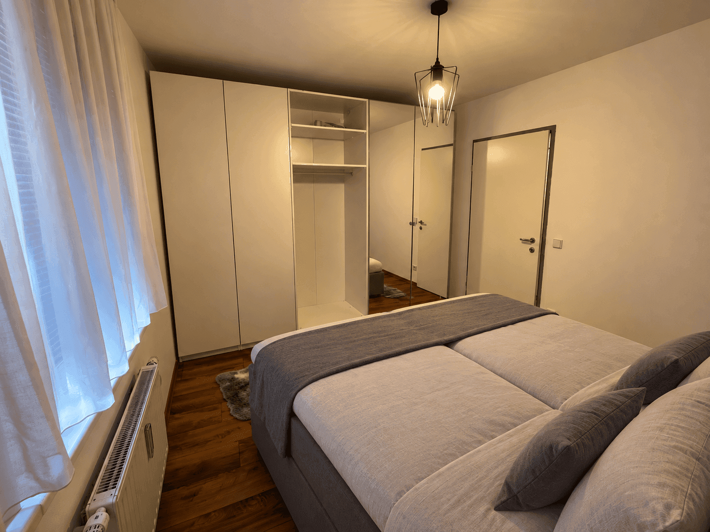Schlafzimmer mit großem Doppelbett und praktischem Einbauschrank mit Spiegeltür.