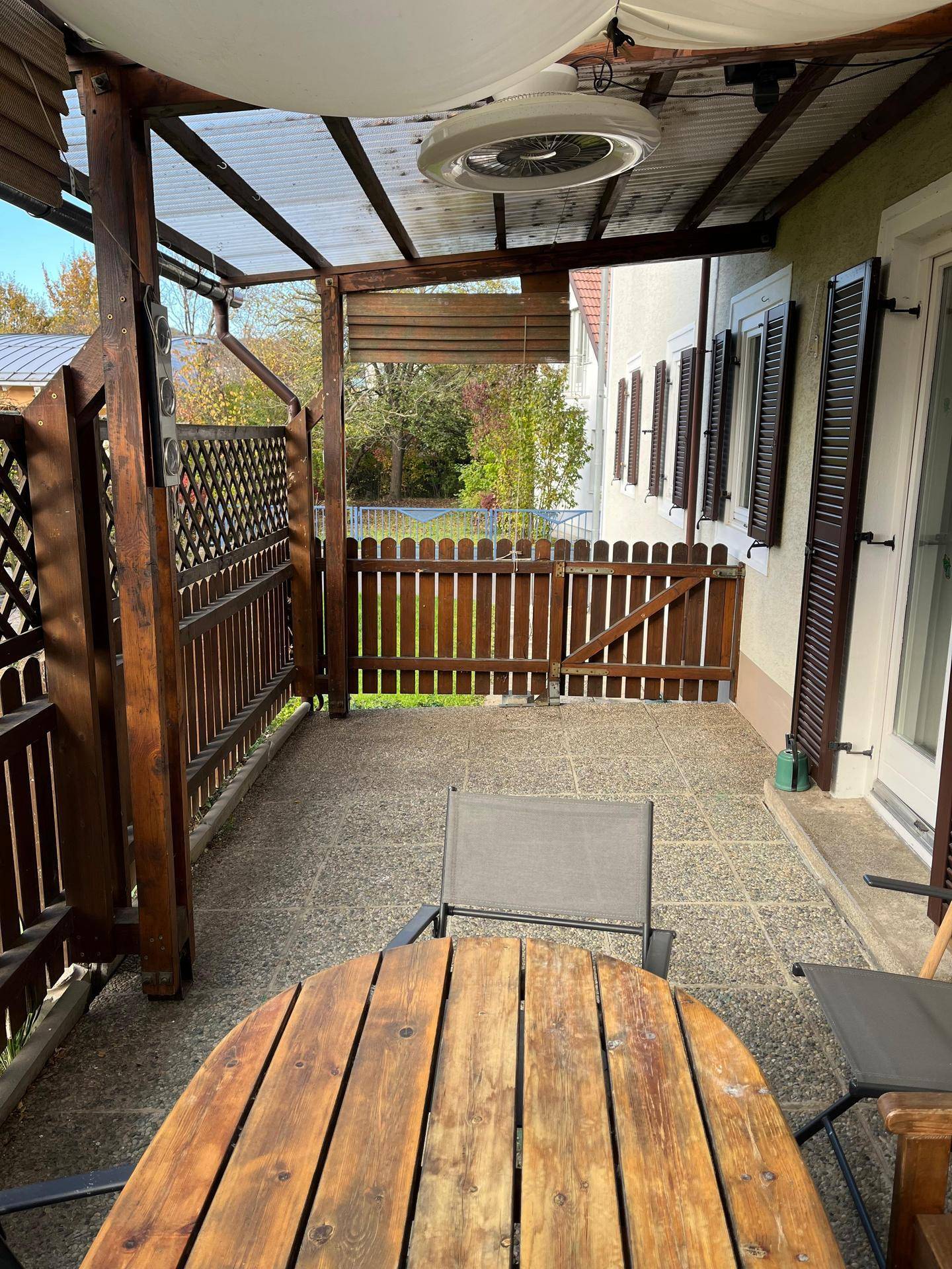 Überdachte Terrasse mit Holztisch, Stühlen und Blick ins Grüne.