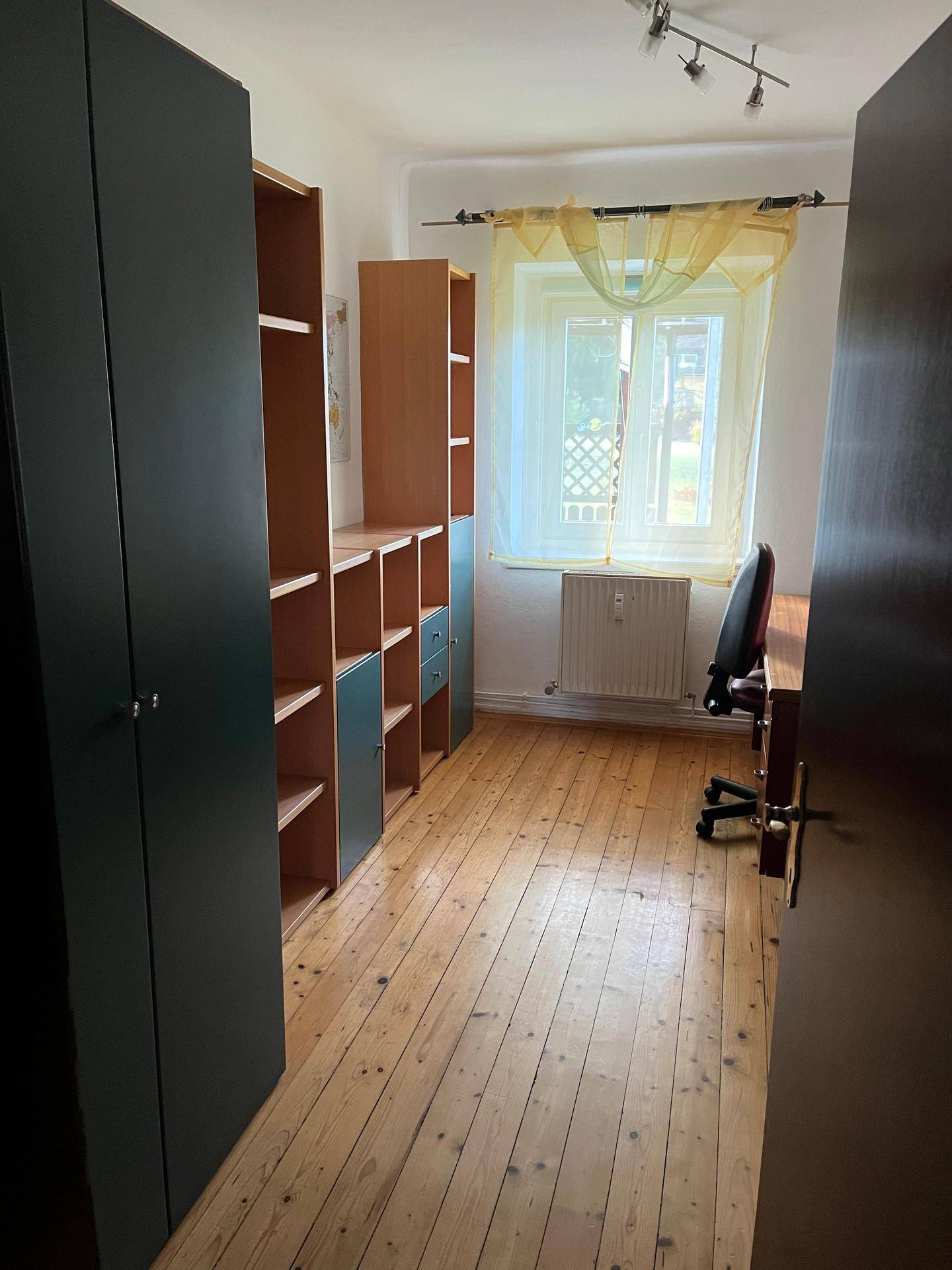 Arbeitszimmer mit Holzregalen, Schrank und Parkettboden.