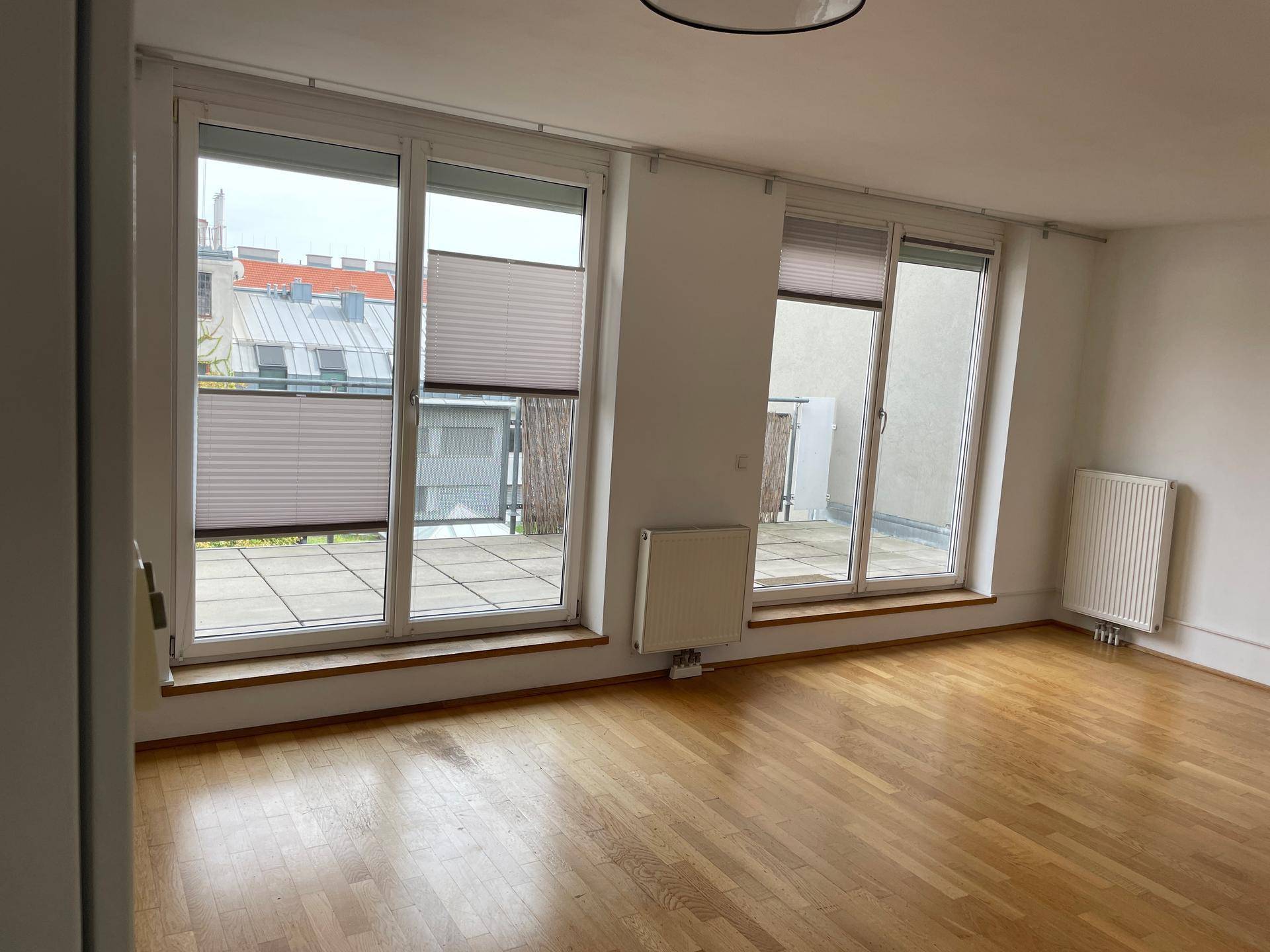 Helles Wohnzimmer mit Parkettboden und großen Fenstern zur Terrasse.