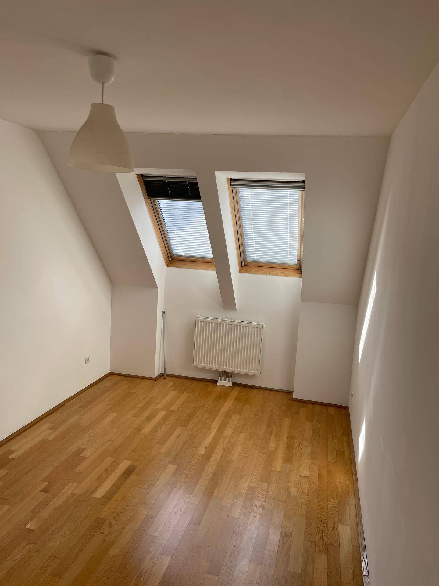 Helles Schlafzimmer im Dachgeschoss mit Parkettboden und Dachfenstern.