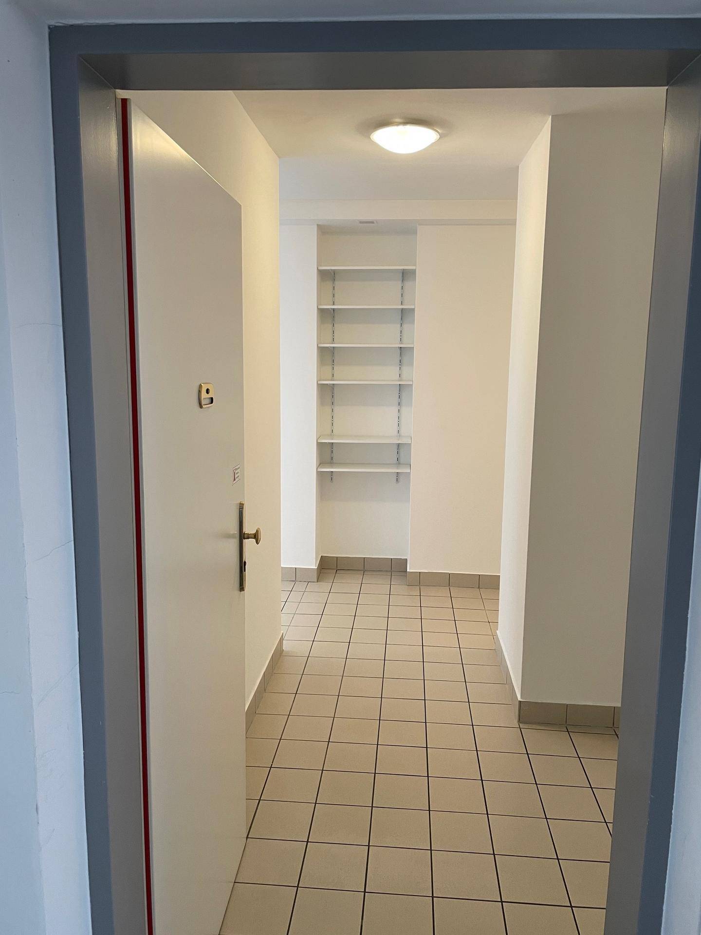 Eingangsbereich der Wohnung mit Fliesenboden und praktischen Einbauregalen.