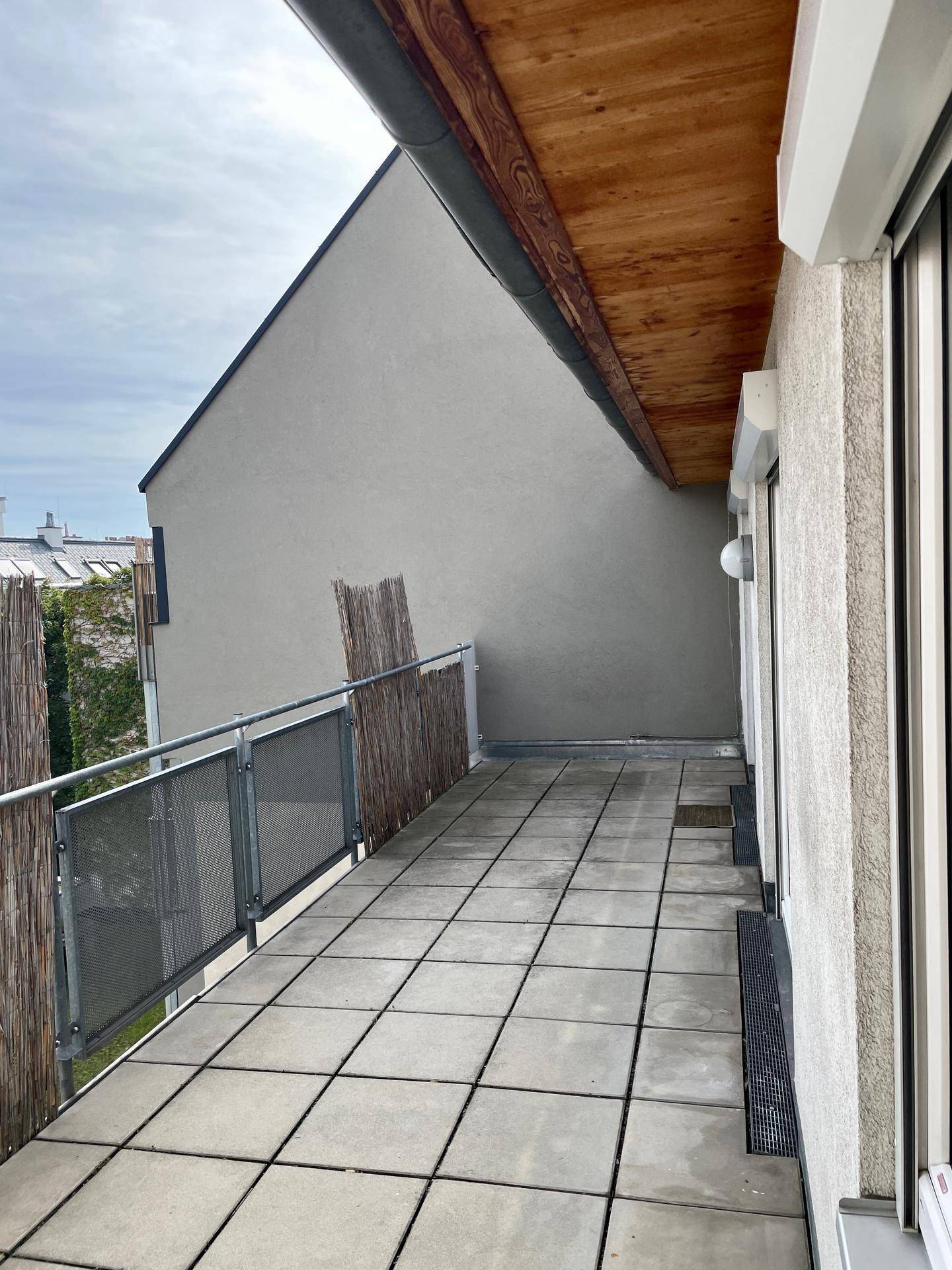 Geräumige Terrasse mit Fliesenboden und Blick auf die umliegenden Dächer.