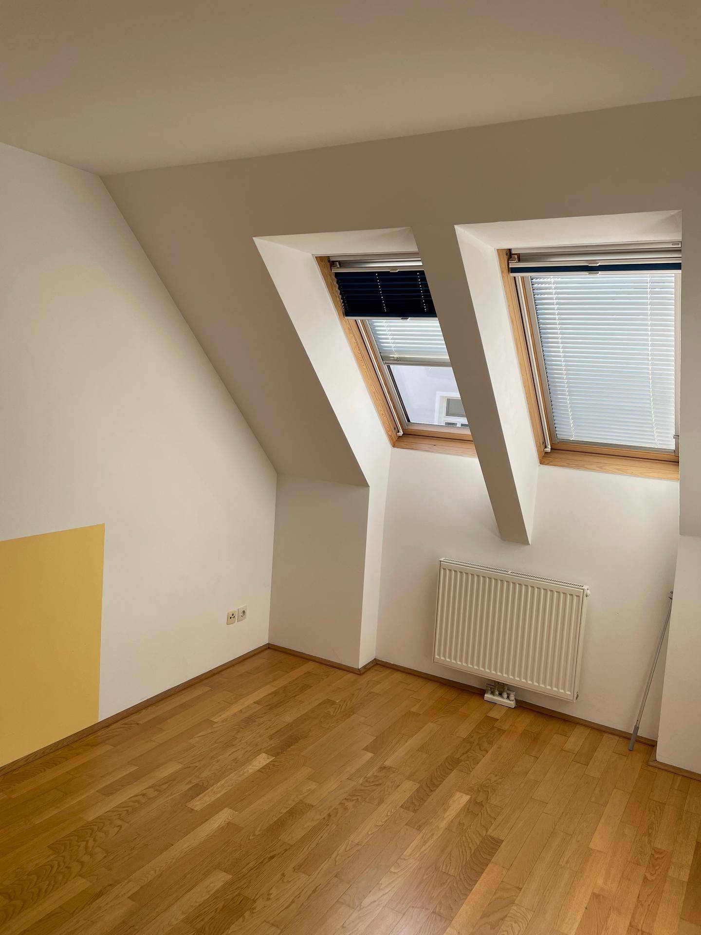 Schlafzimmer mit Parkettboden, Dachschrägen und zwei Dachfenstern.
