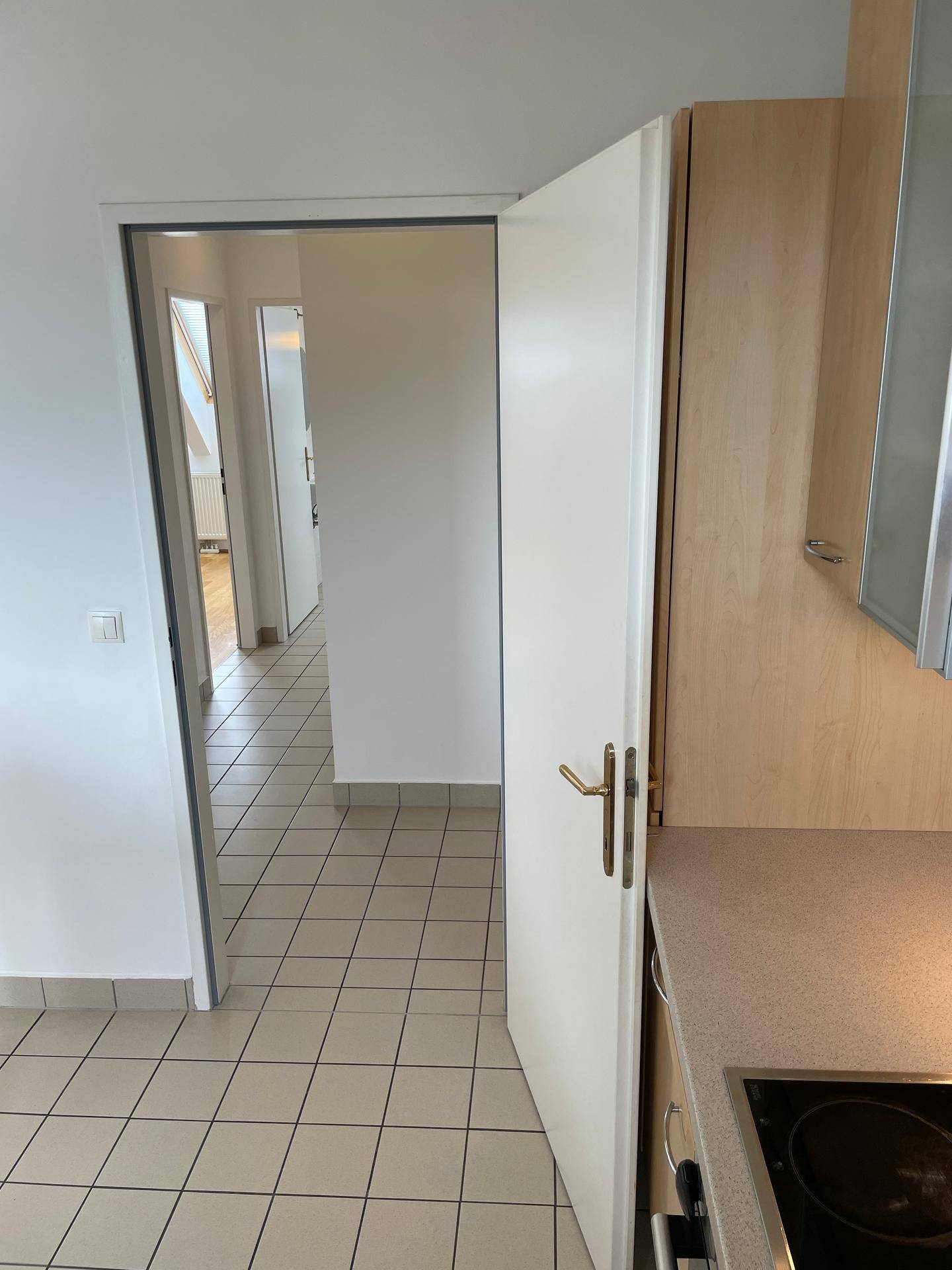 Blick von der Küche in den Flur mit Fliesenboden und weiteren Räumen.