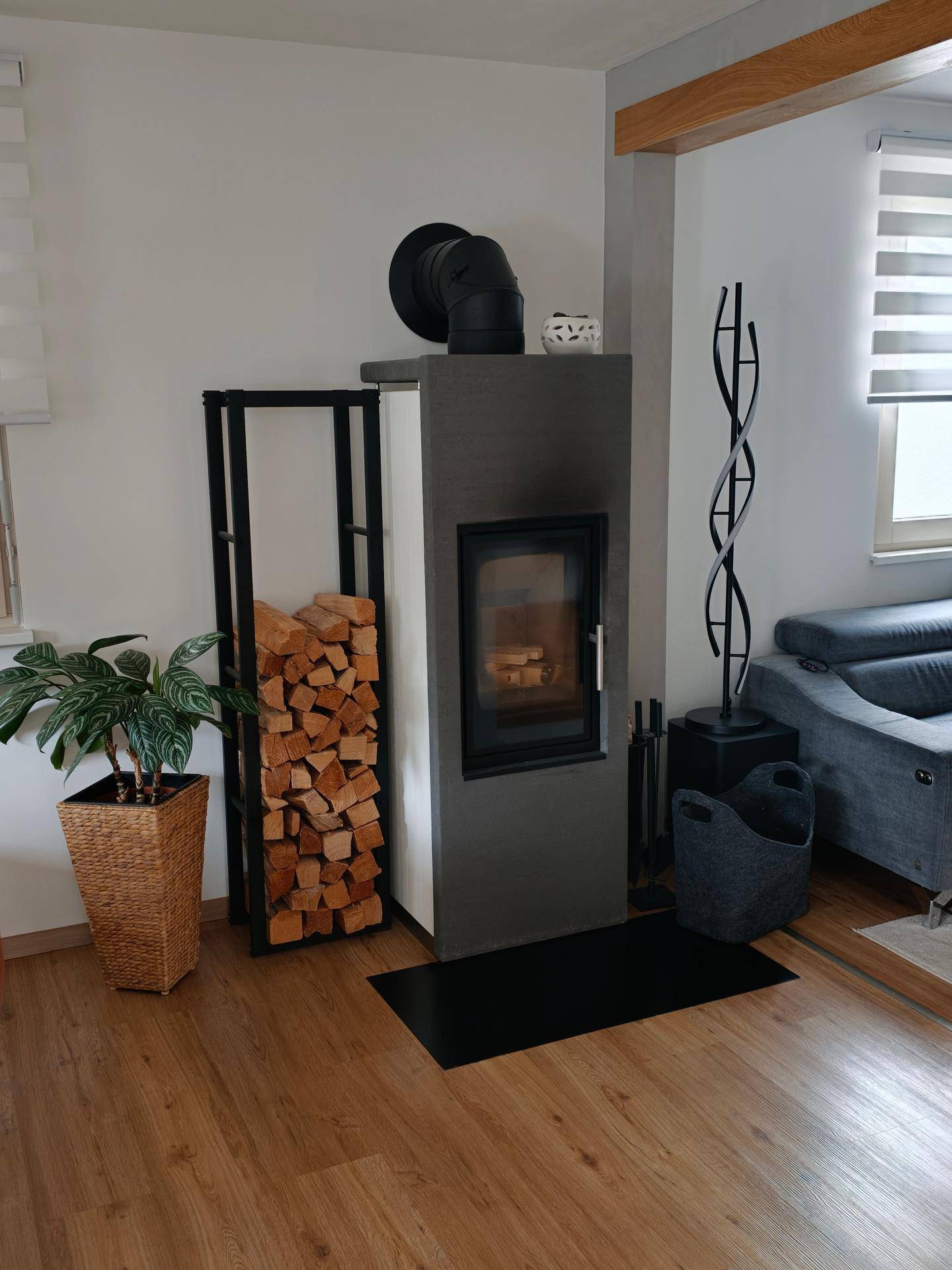 Helles Wohnzimmer mit modernem Kaminofen, Holzstapel und Laminatboden für gemütliche Abende.