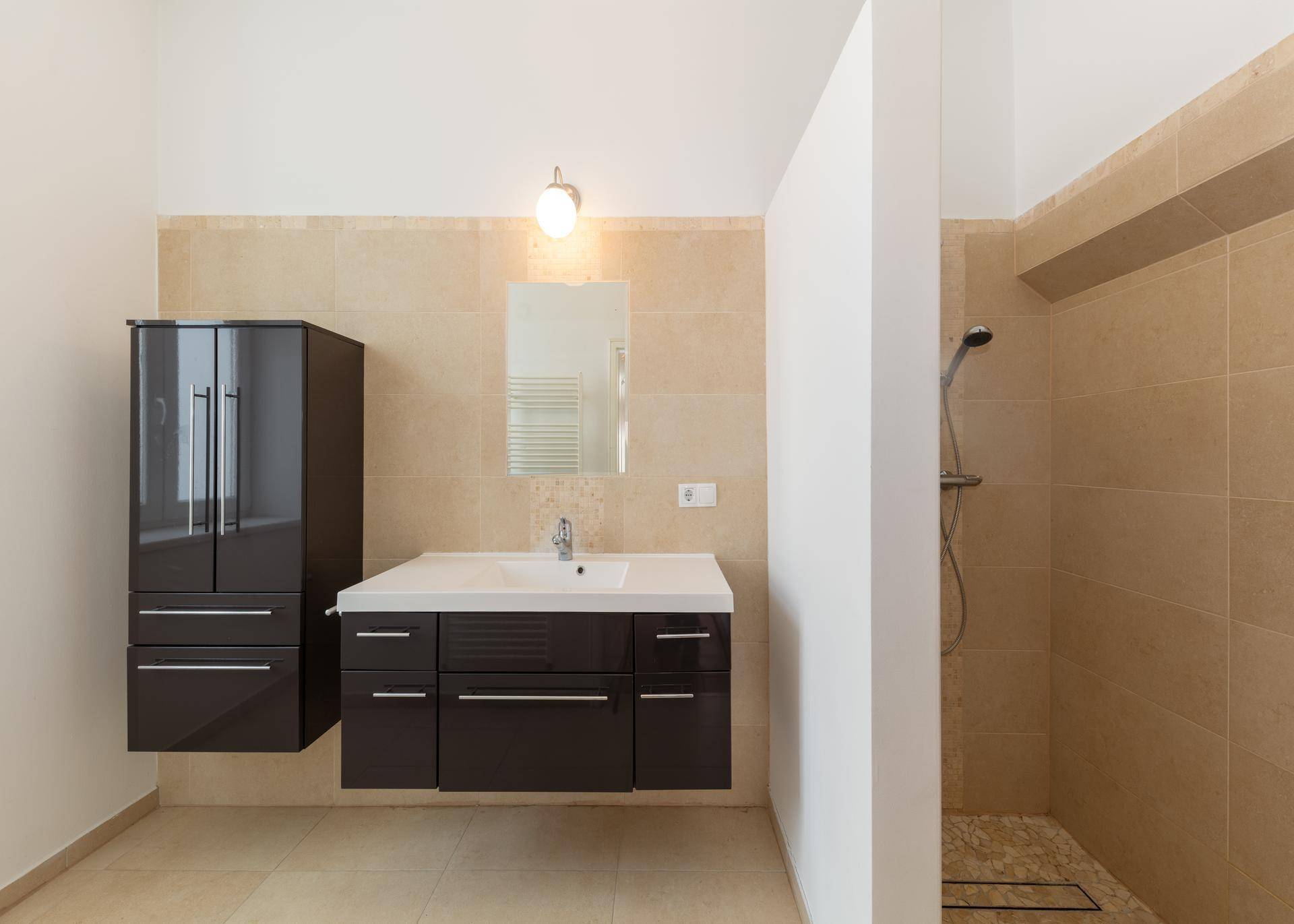 Modernes Badezimmer mit beigefarbenen Fliesen, Waschtisch und begehbarer Dusche.