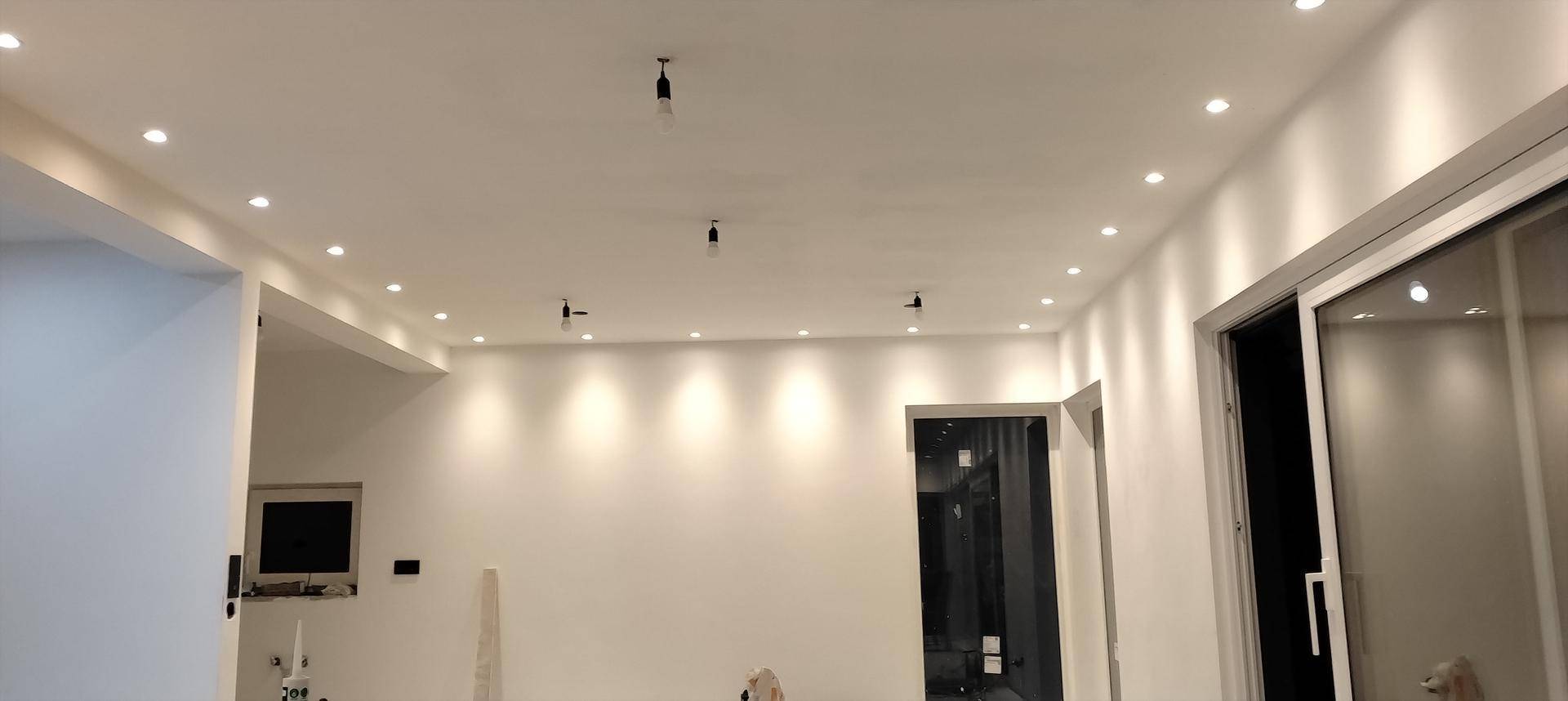 Innenraum im Bau mit weiß gestrichenen Wänden und zahlreichen Deckenstrahlern für moderne Beleuchtung.