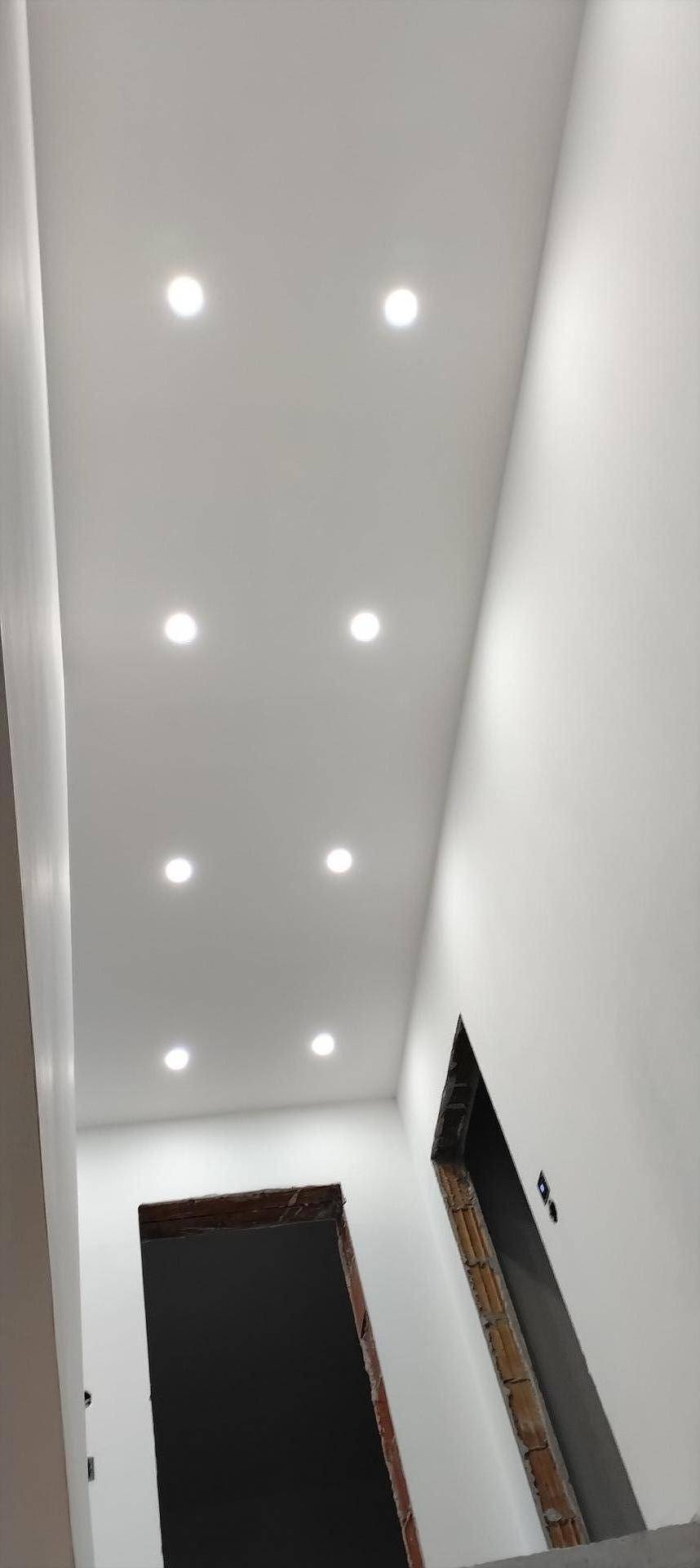 Flur oder Treppenhaus im Bau mit weißer Decke und eingelassenen Deckenleuchten für eine moderne Optik.