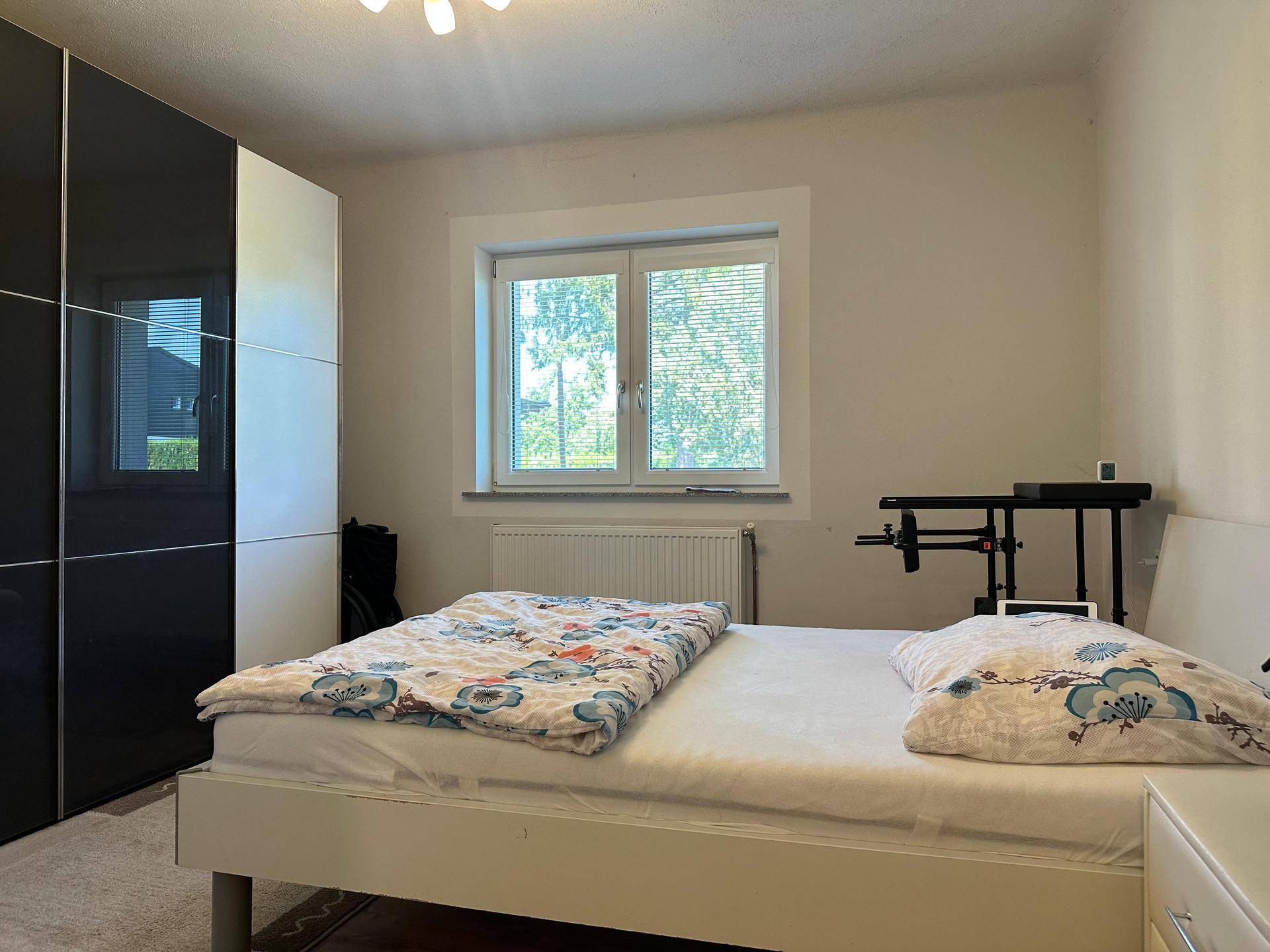 Gemütliches Schlafzimmer mit Doppelbett, großem Kleiderschrank und Fenster mit Blick ins Grüne.