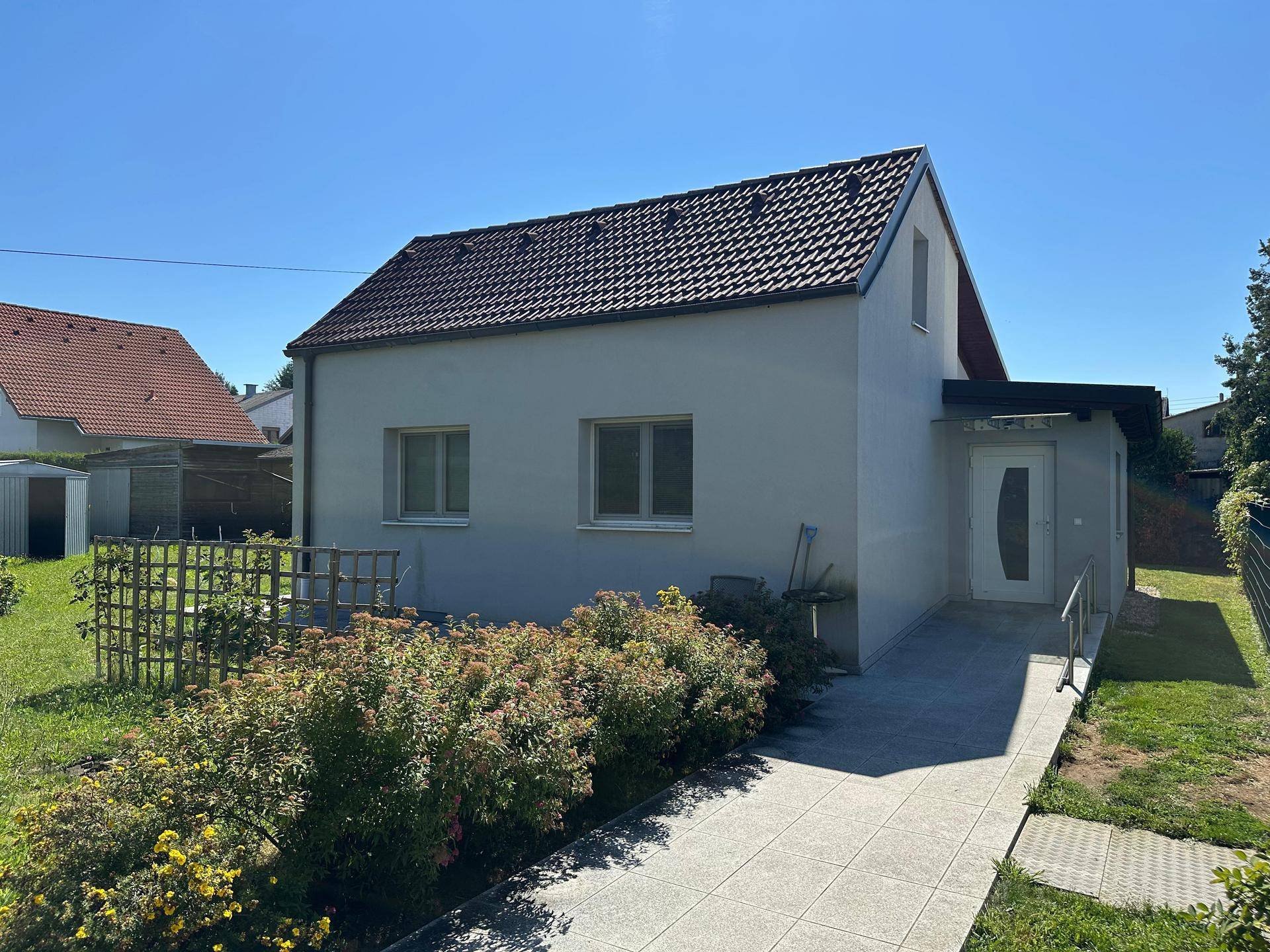 Ansicht des Hauses von der Seite mit barrierefreiem Eingang und gepflegtem Vorgarten.