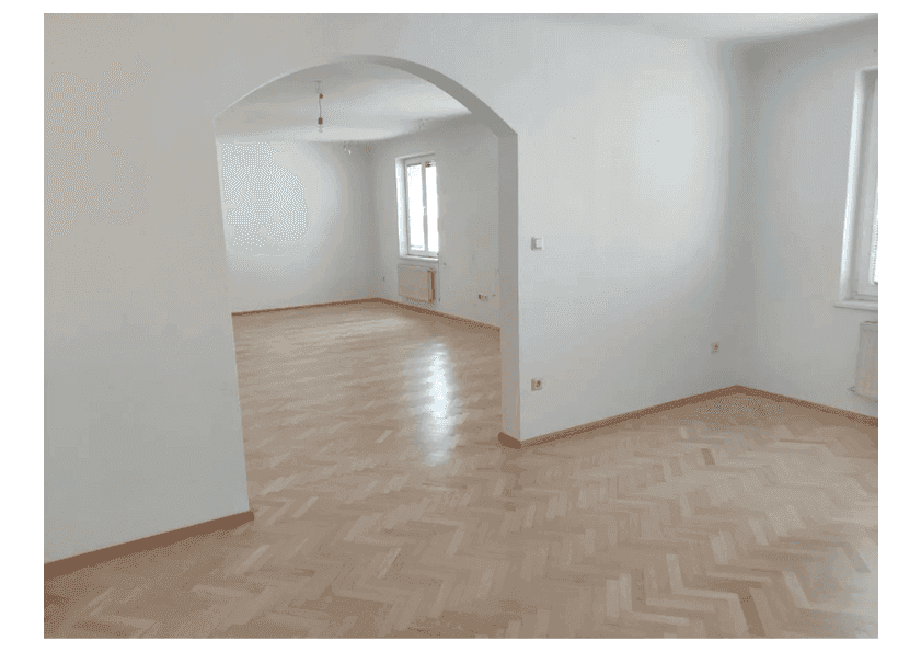 Heller, leerer Wohnbereich mit Fischgrätparkett und dekorativem Rundbogen.