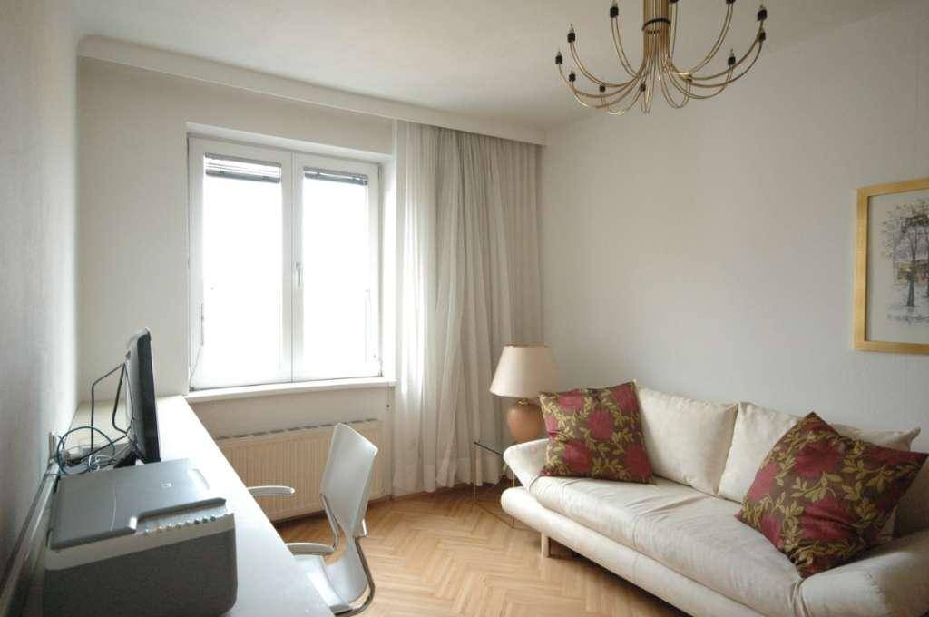 Helles Arbeitszimmer mit Schreibtisch, Computer und einem bequemen Sofa.