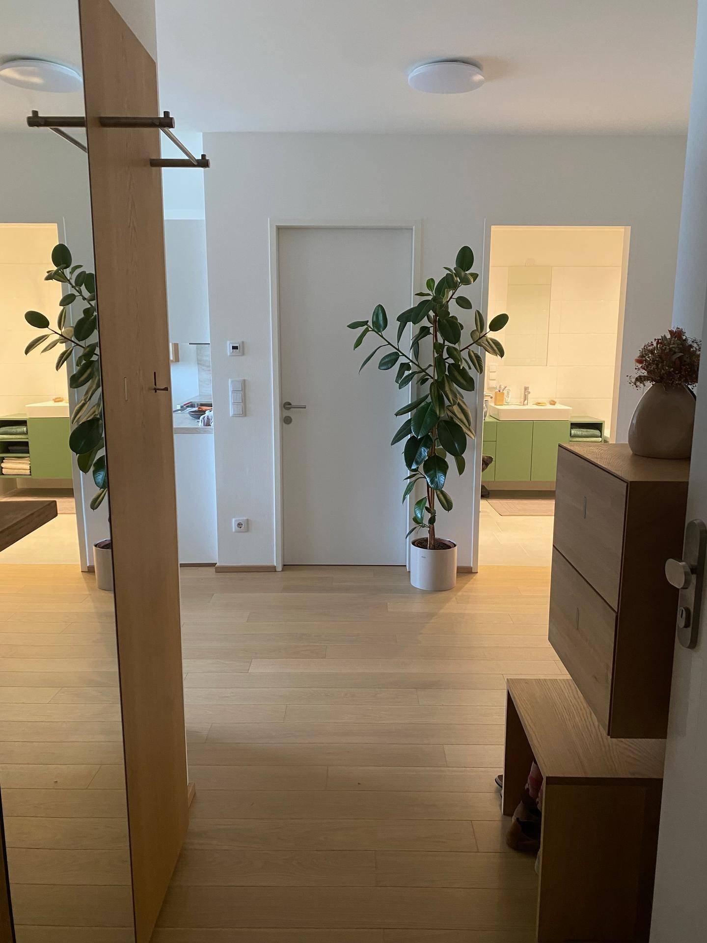 Heller Flur mit Holzboden und Blick in angrenzende Räume, inklusive Badezimmer.