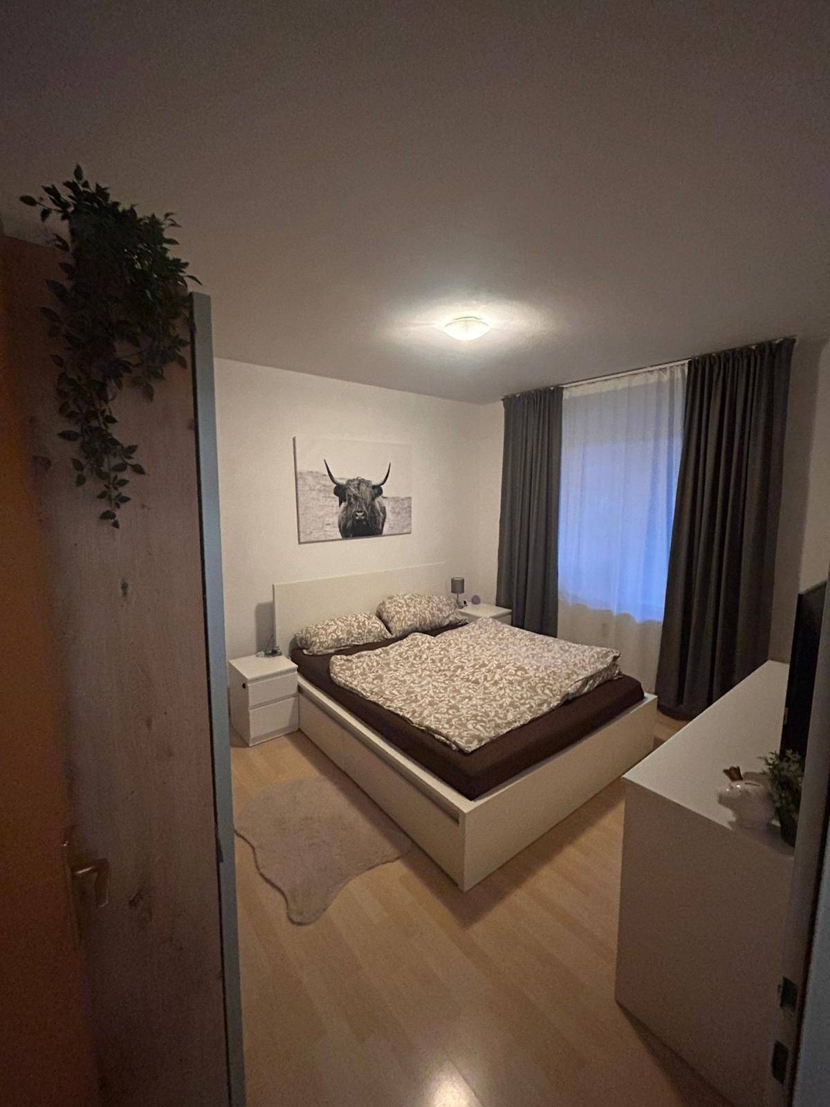 Schlafzimmer mit Doppelbett, Nachttischen und dunklen Vorhängen für erholsamen Schlaf.