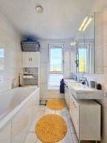 Geräumiges Badezimmer mit Doppelwaschbecken, Badewanne und Fenster für natürliches Licht.