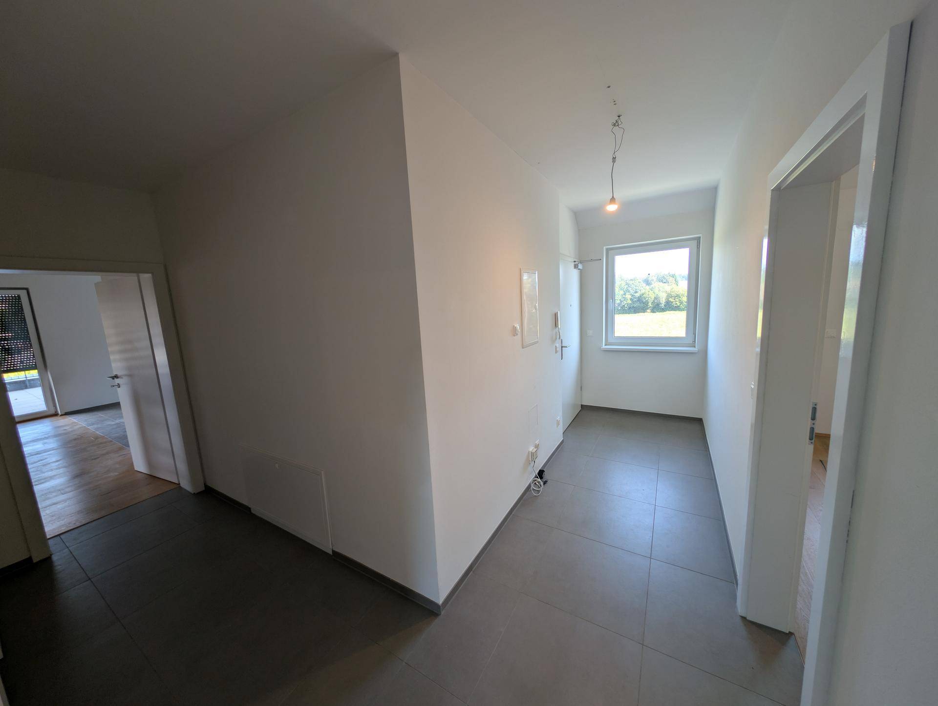 Heller Eingangsbereich mit Fliesenboden und Fenster, das Tageslicht hereinlässt.