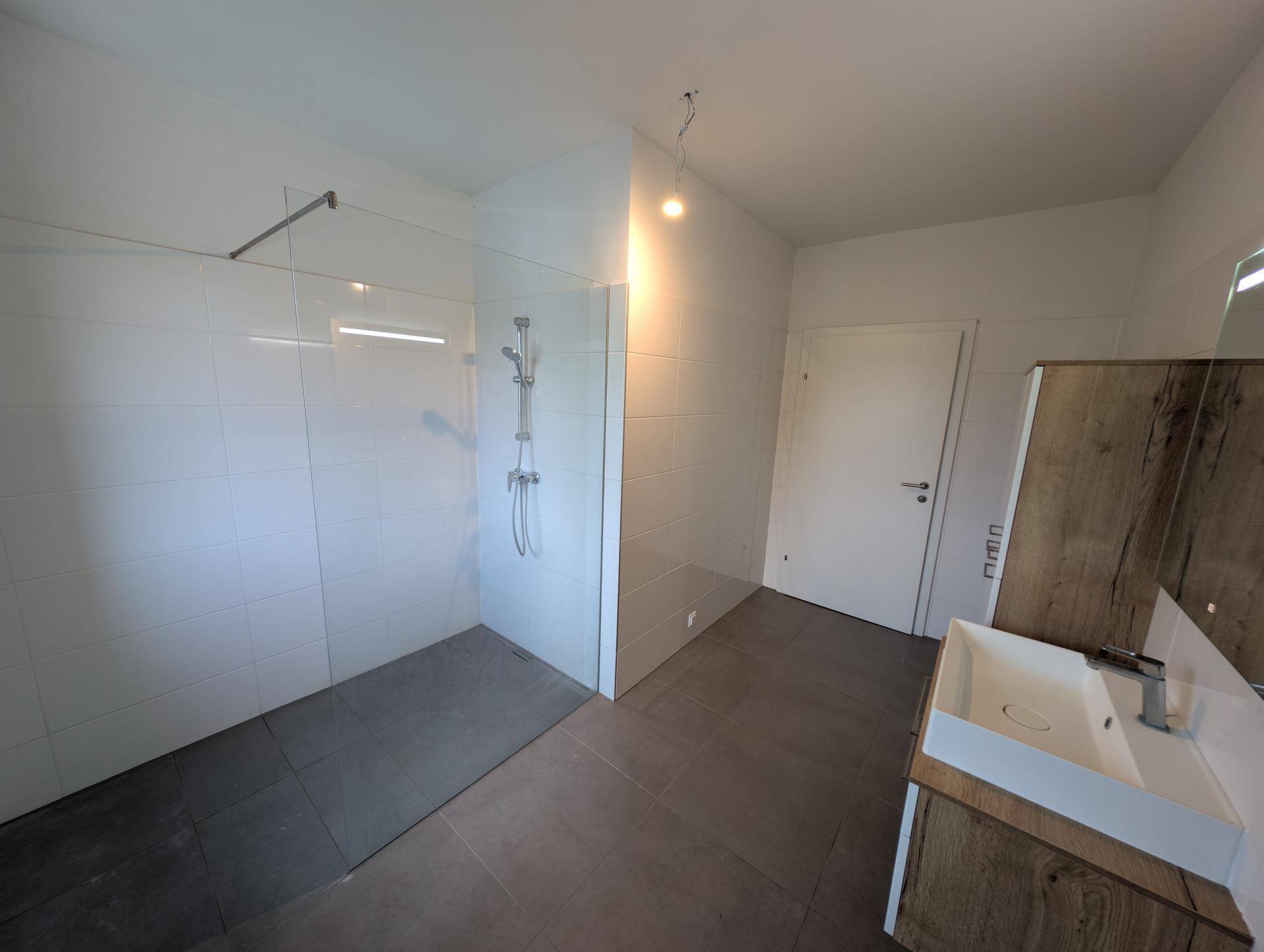 Geräumiges Badezimmer mit begehbarer Dusche, Einzelwaschbecken und modernen Fliesen.
