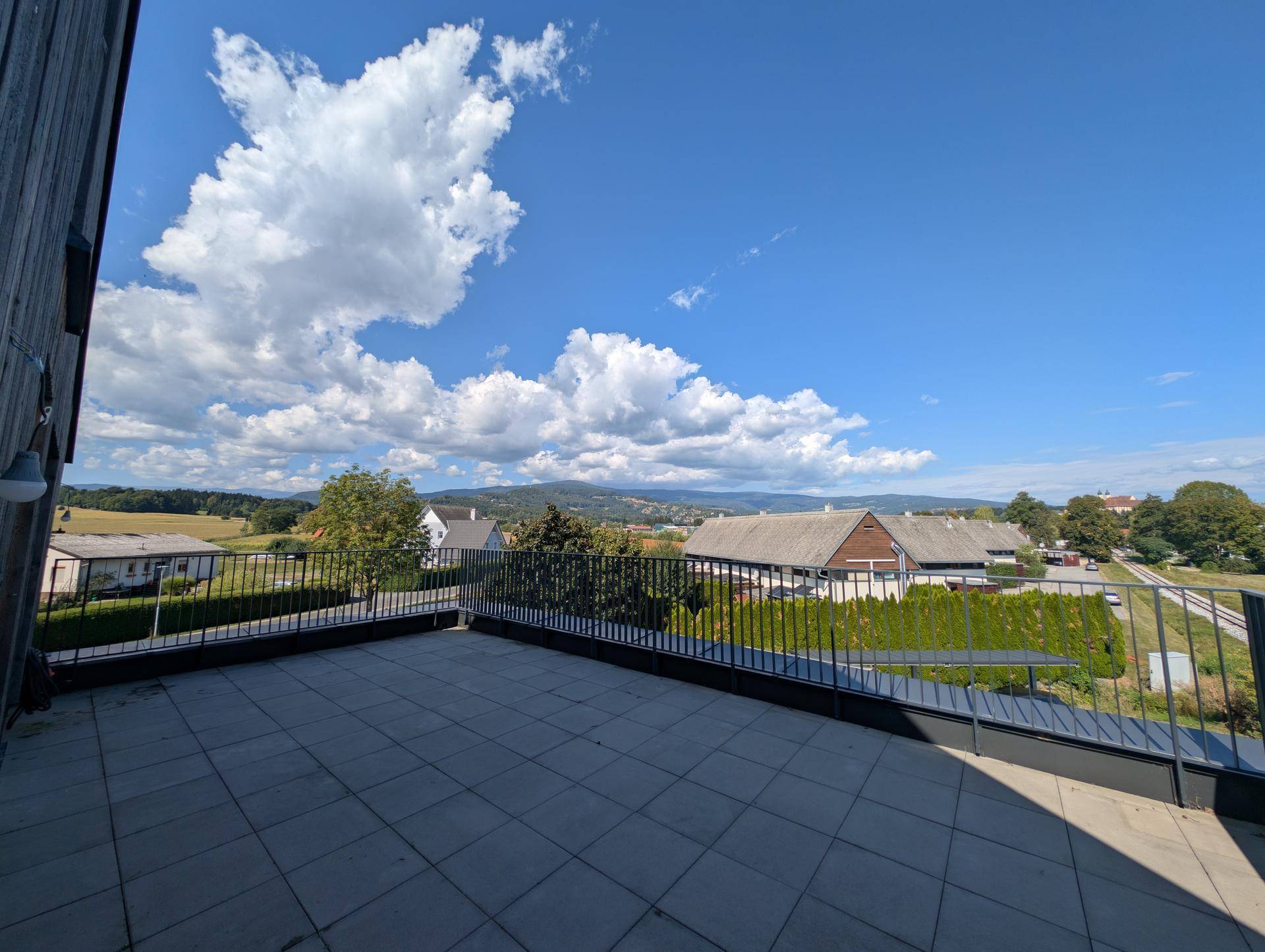 Große Außenterrasse mit Fliesenboden und Panoramablick auf die Landschaft und Berge.