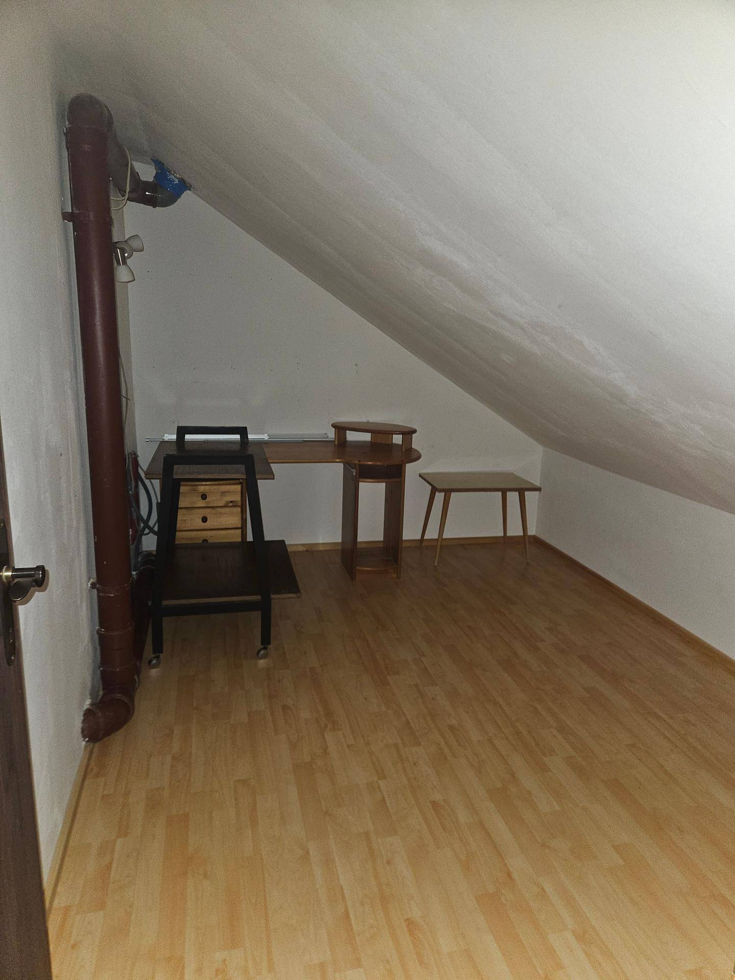 Vielseitiger Raum im Dachgeschoss mit Schreibtisch und hellem Laminatboden.