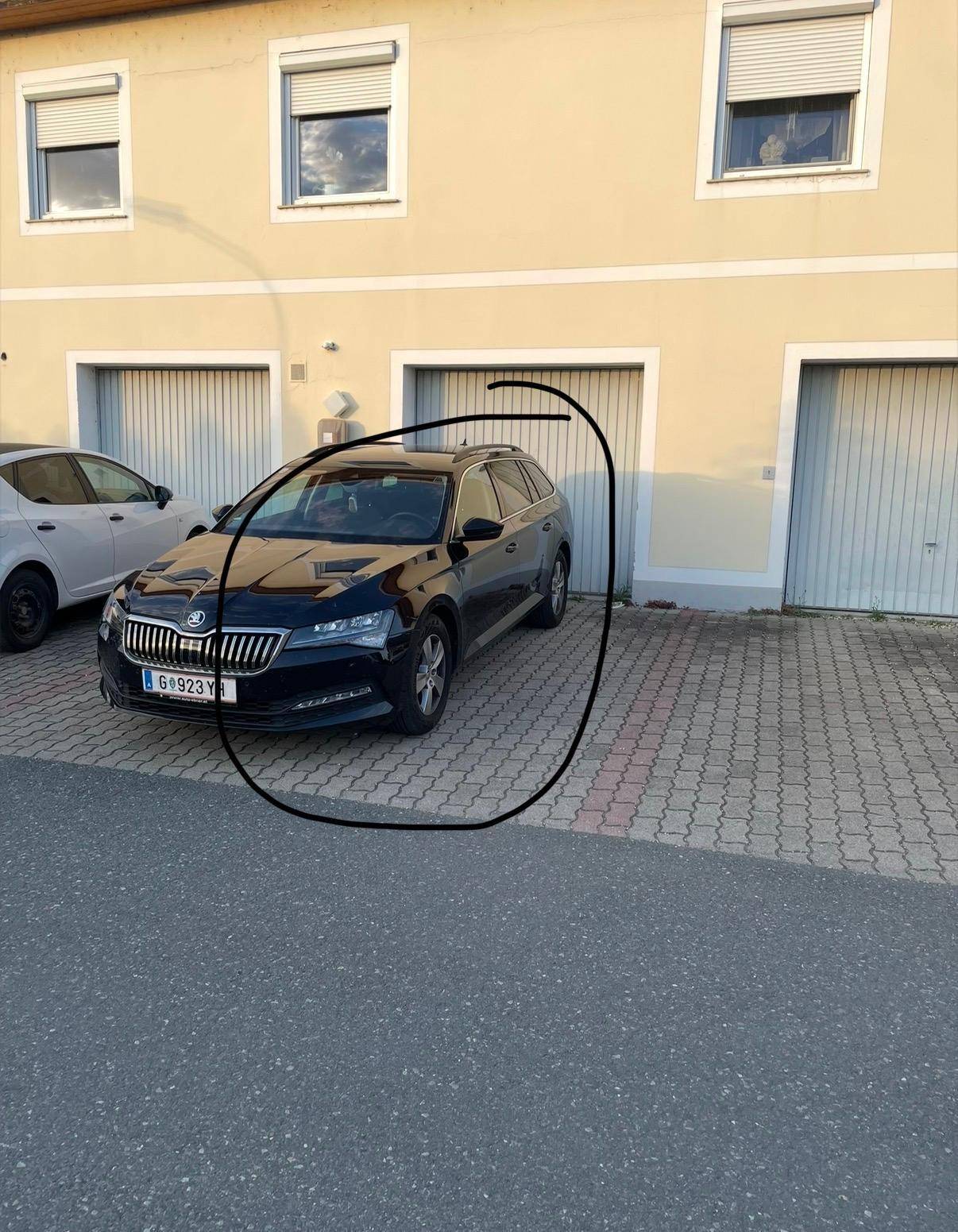 Außenansicht des Hauses mit Garagen und einem geparkten Auto davor.
