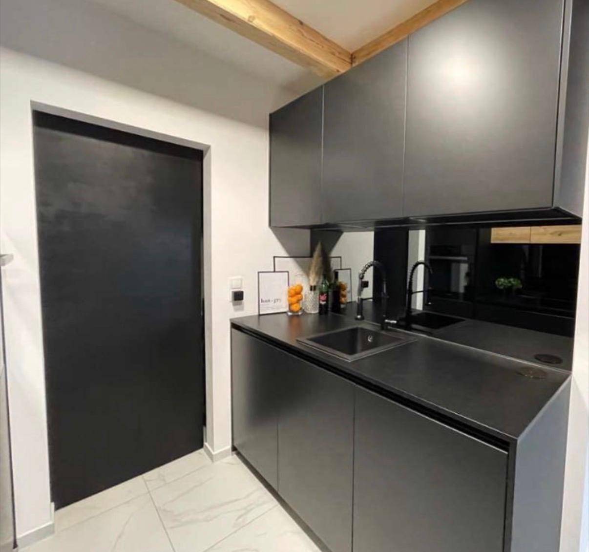 Teil einer modernen schwarzen Küche mit Spüle, Schränken und minimalistischem Design.