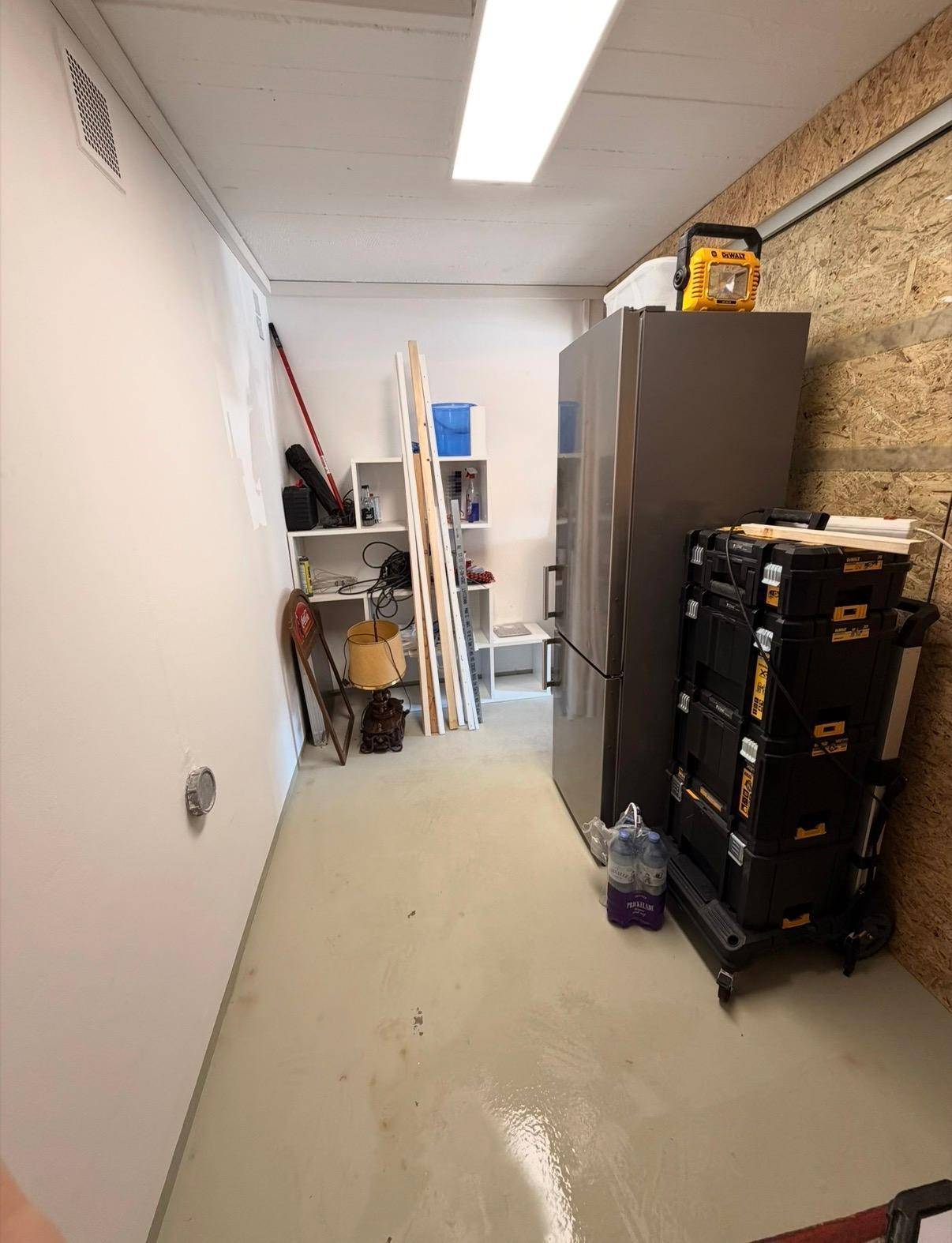 Praktischer Abstellraum mit Kühlschrank, Regalen und ausreichend Stauraum.