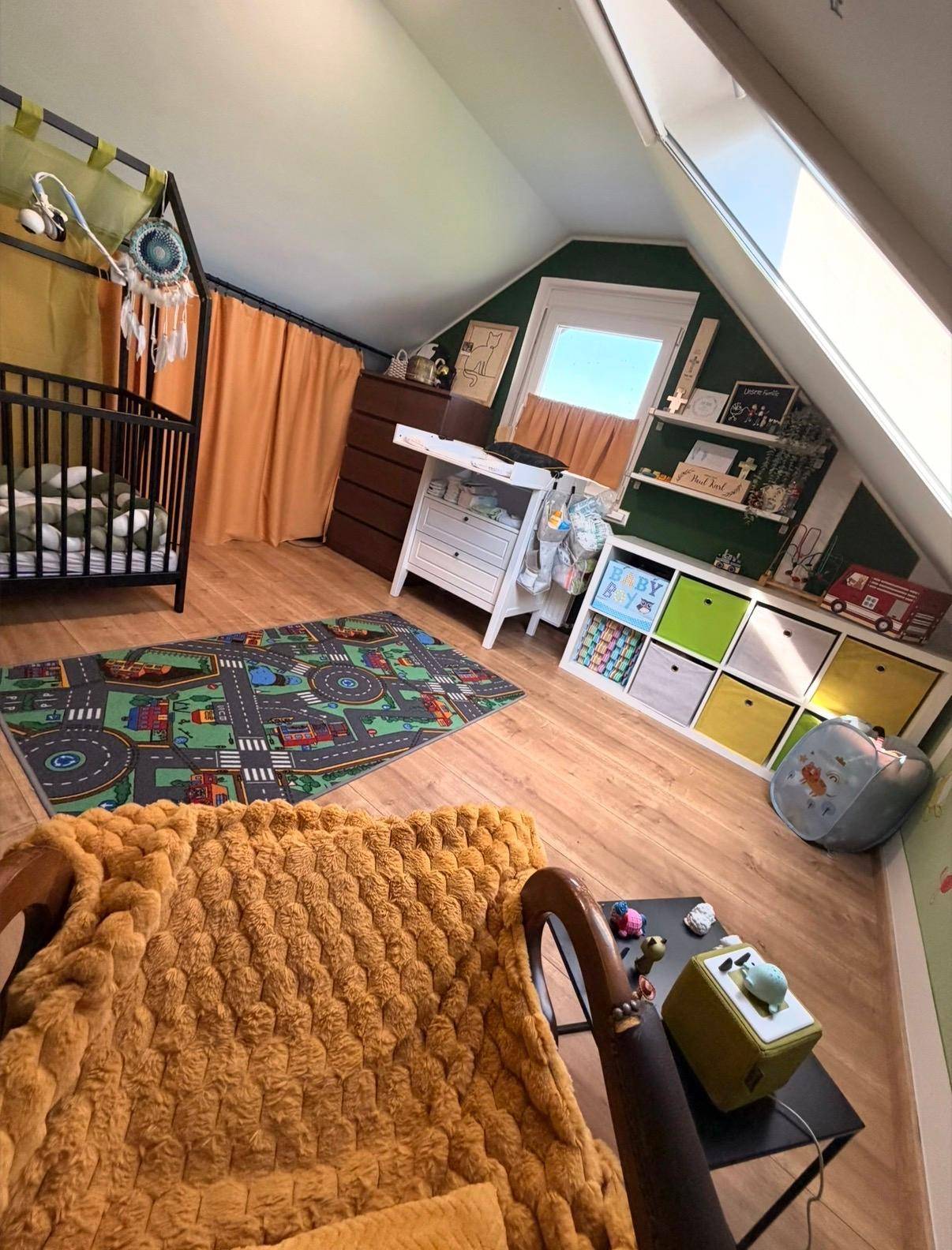 Helles Kinderzimmer im Dachgeschoss mit Babybett, Wickeltisch und Dachfenster.