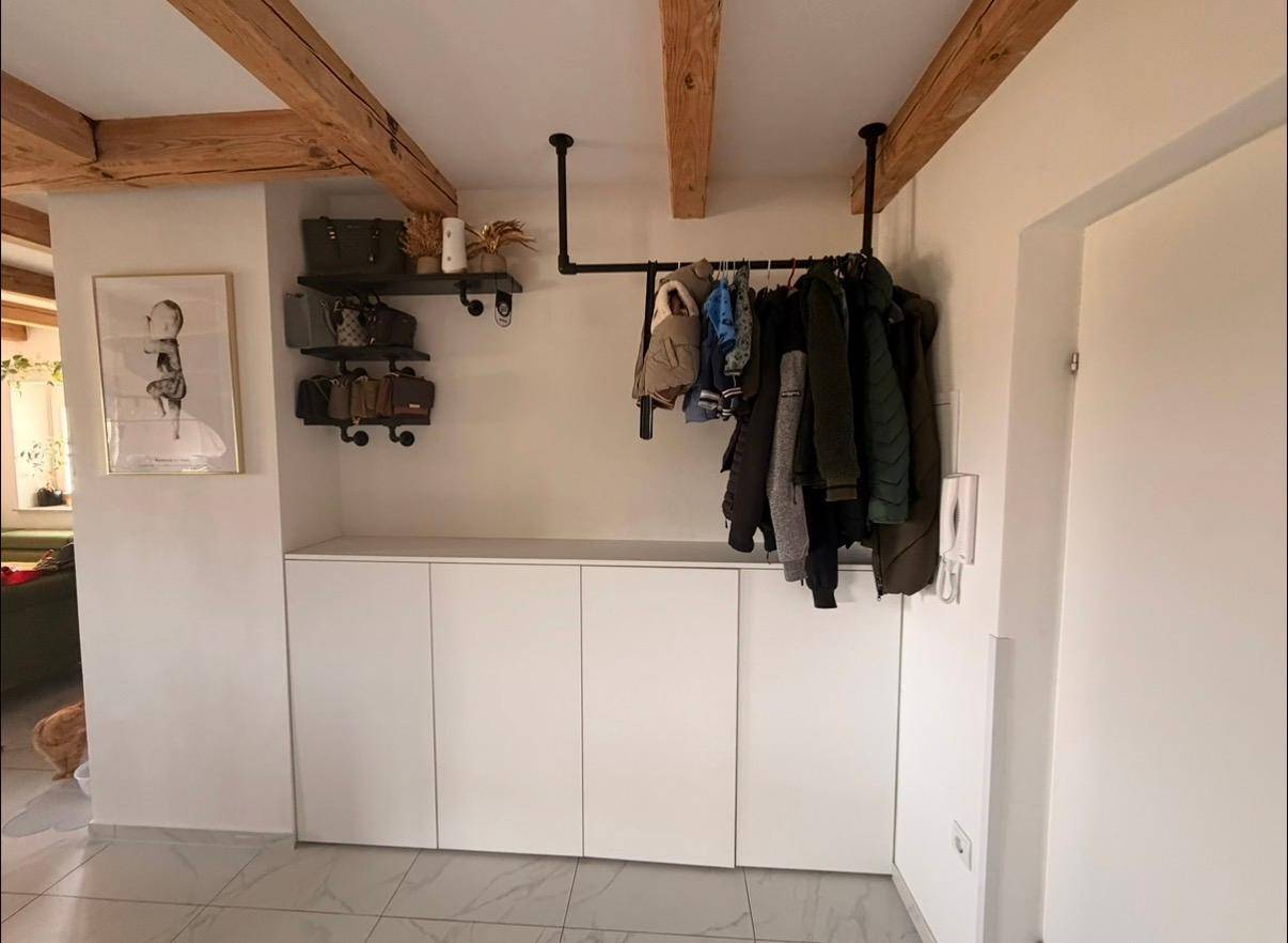 Funktionaler Flur mit offener Garderobe, Stauraum und rustikalen Holzbalken.