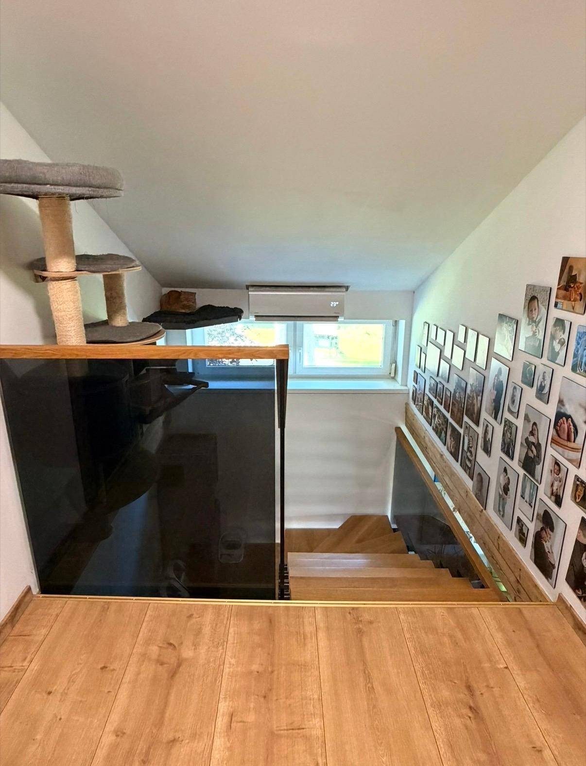 Blick vom Dachgeschoss die Treppe hinunter, mit Fenster und Katzenbaum.