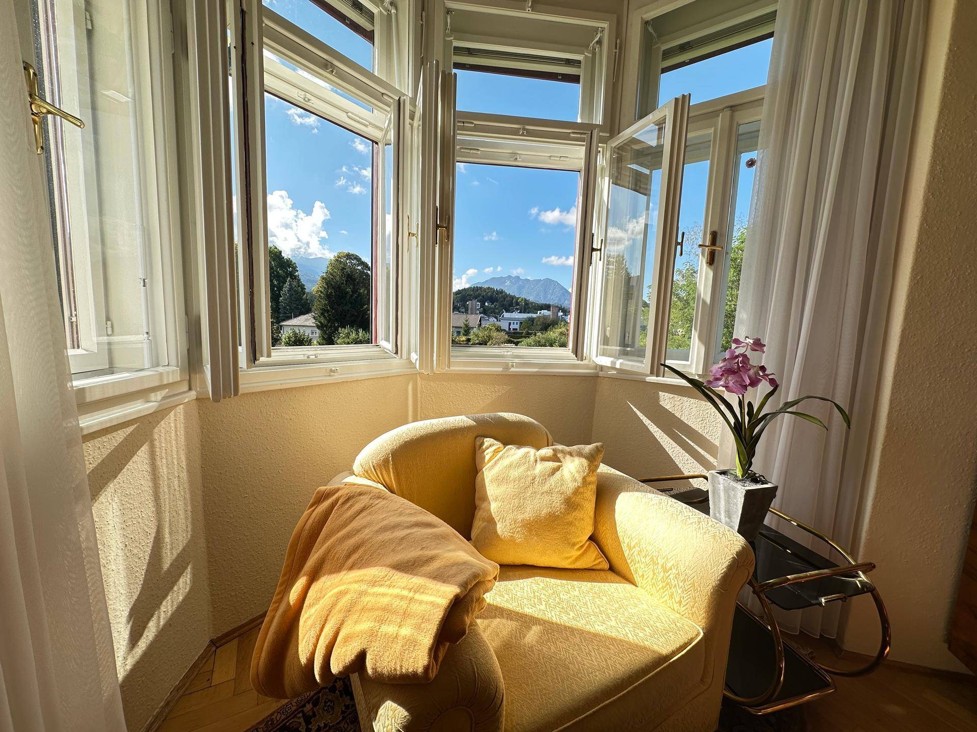 Sonnendurchfluteter Erker mit bequemem Sessel und weitem Blick auf die Berge und die Umgebung.