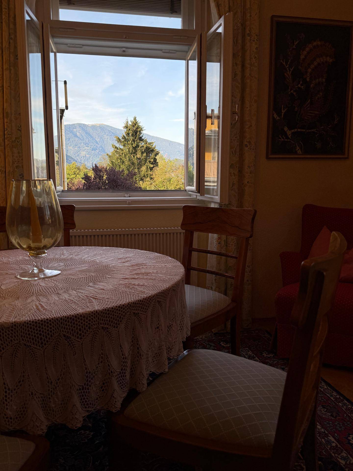 Gemütlicher Essbereich mit rundem Tisch und Stühlen, mit Blick auf die Berge durch das Fenster.