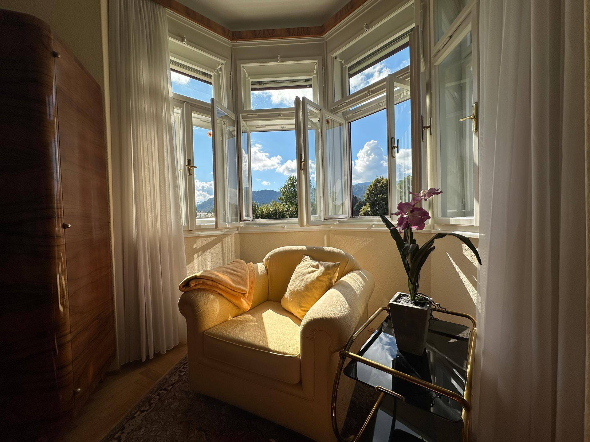 Gemütlicher Erkerbereich mit Sessel und Blick ins Grüne durch die großen Fenster.