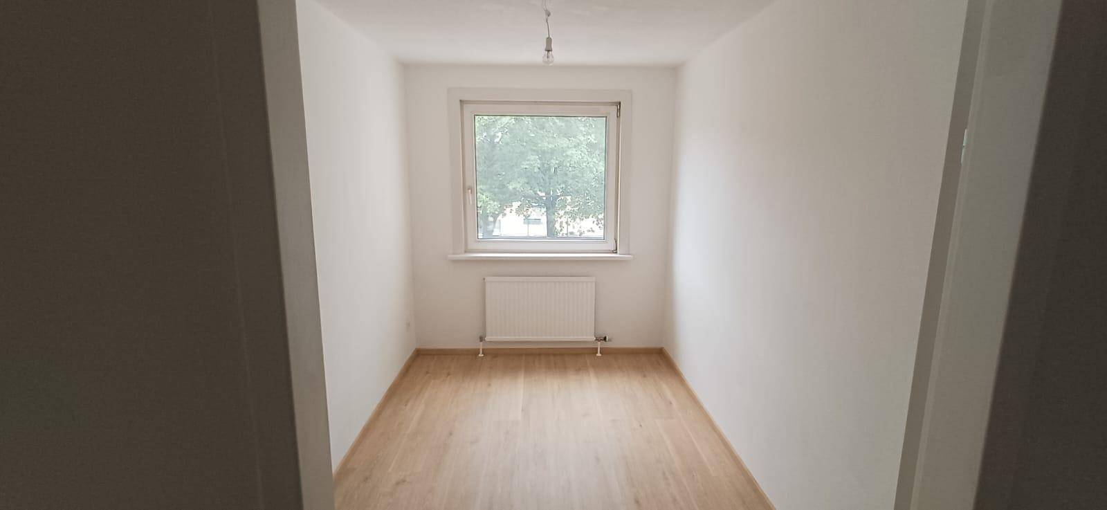 Kleiner, heller Raum mit Holzfußboden und Fenster, ideal als Büro oder Kinderzimmer nutzbar.
