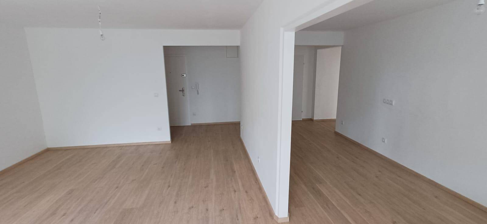 Offener Wohnbereich mit hellem Holzfußboden und weißen Wänden, bereit zur individuellen Gestaltung.