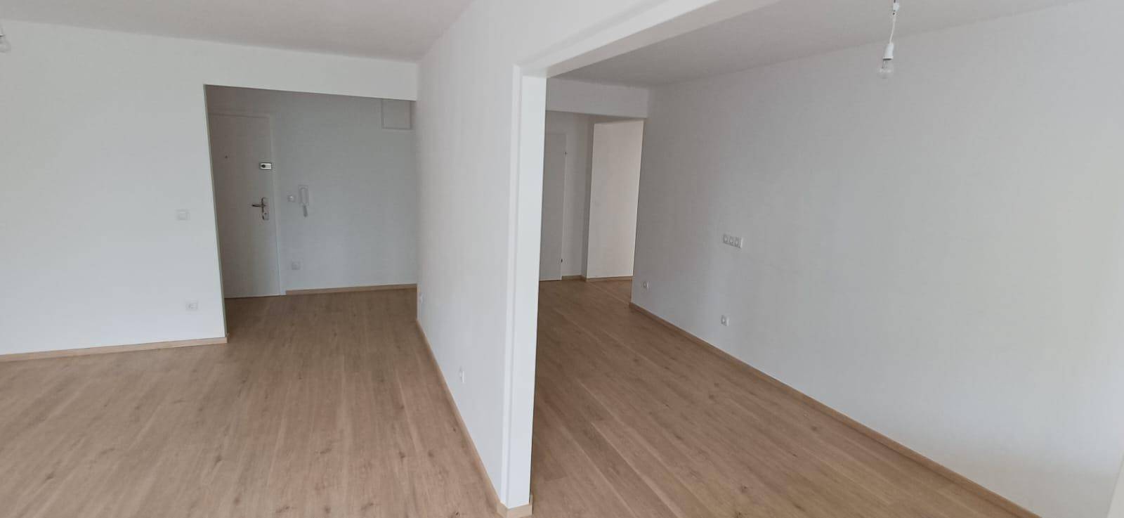 Offener Wohnbereich mit hellem Holzfußboden und weißen Wänden, bereit zur individuellen Gestaltung.