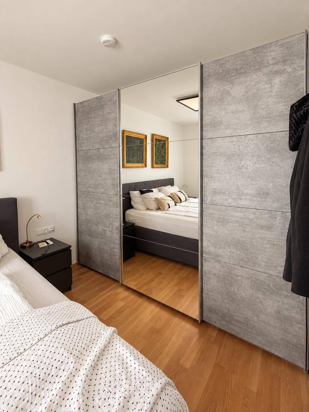 Schlafzimmer mit großem Bett und modernem Kleiderschrank mit Spiegeltüren.