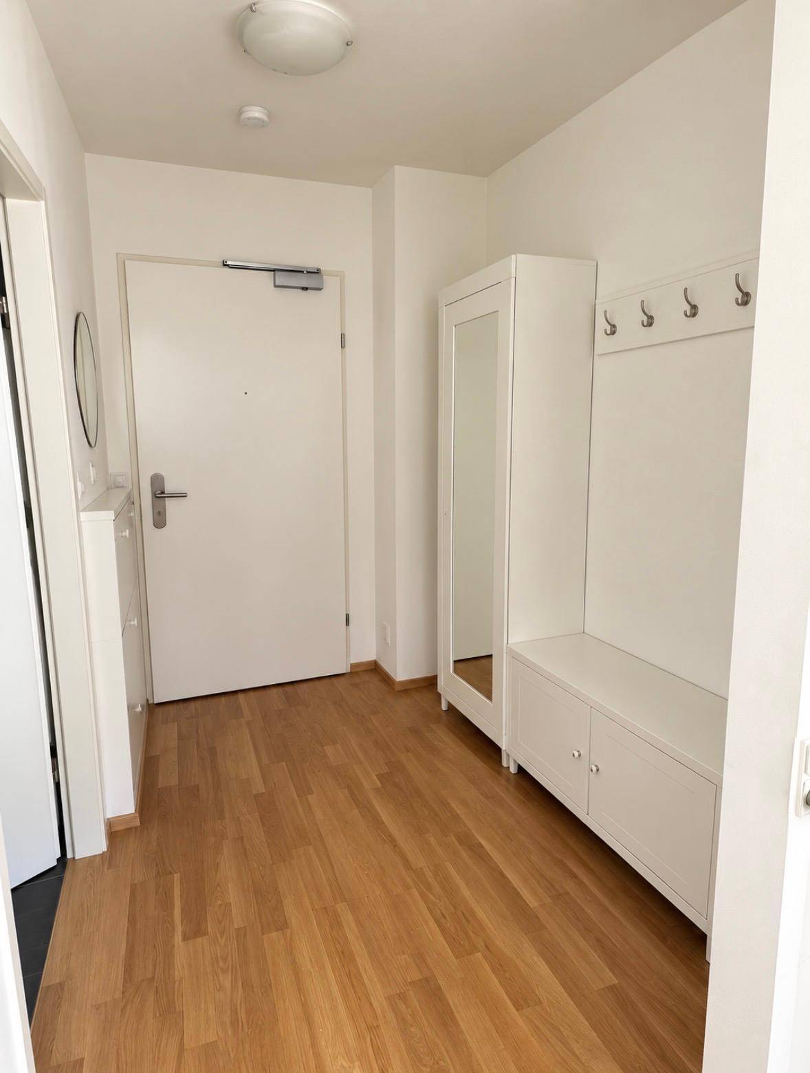 Heller Eingangsbereich mit Garderobe, Spiegel und Laminatboden.