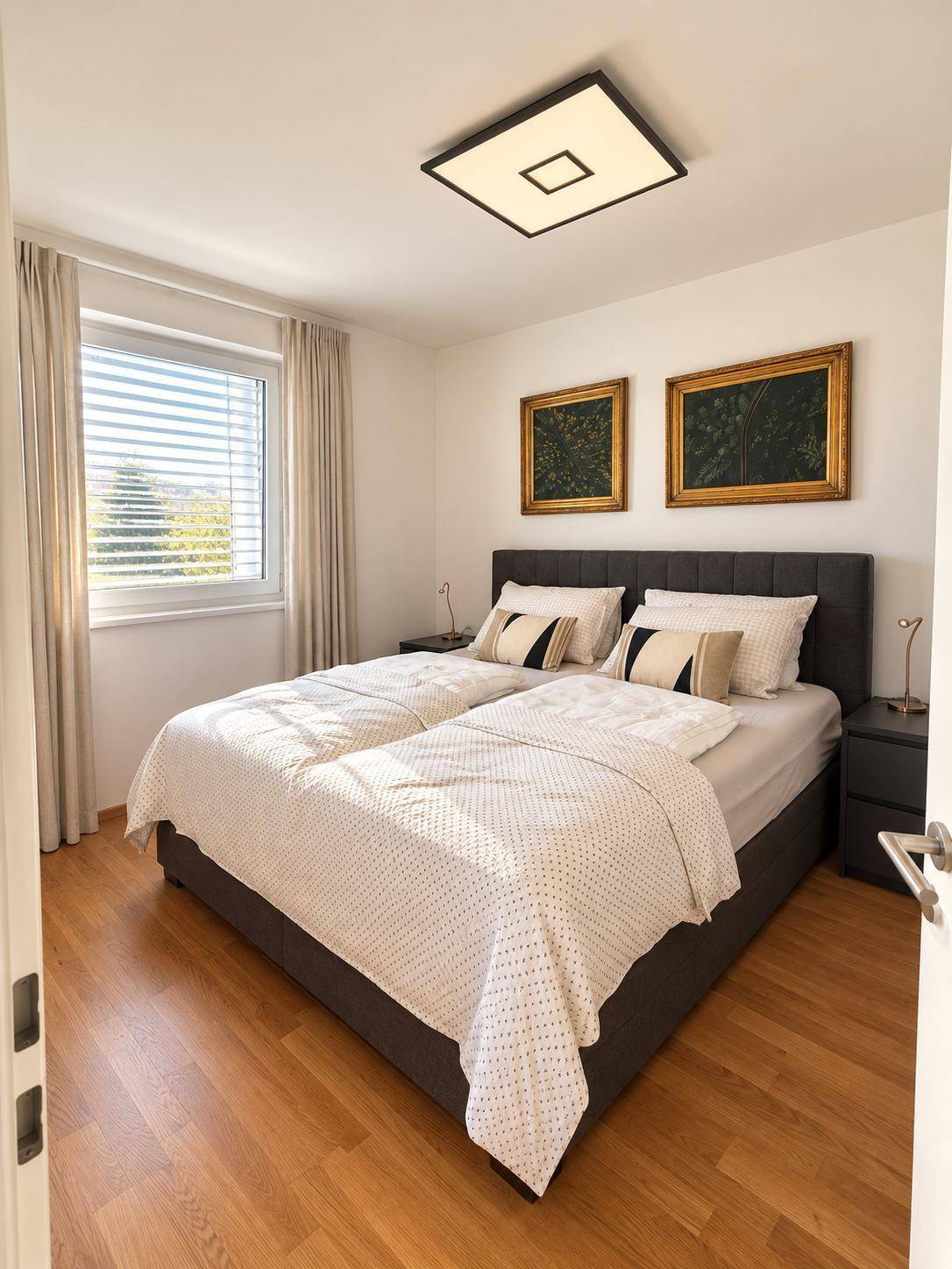 Helles Schlafzimmer mit Doppelbett, Fenster und Blick ins Grüne.